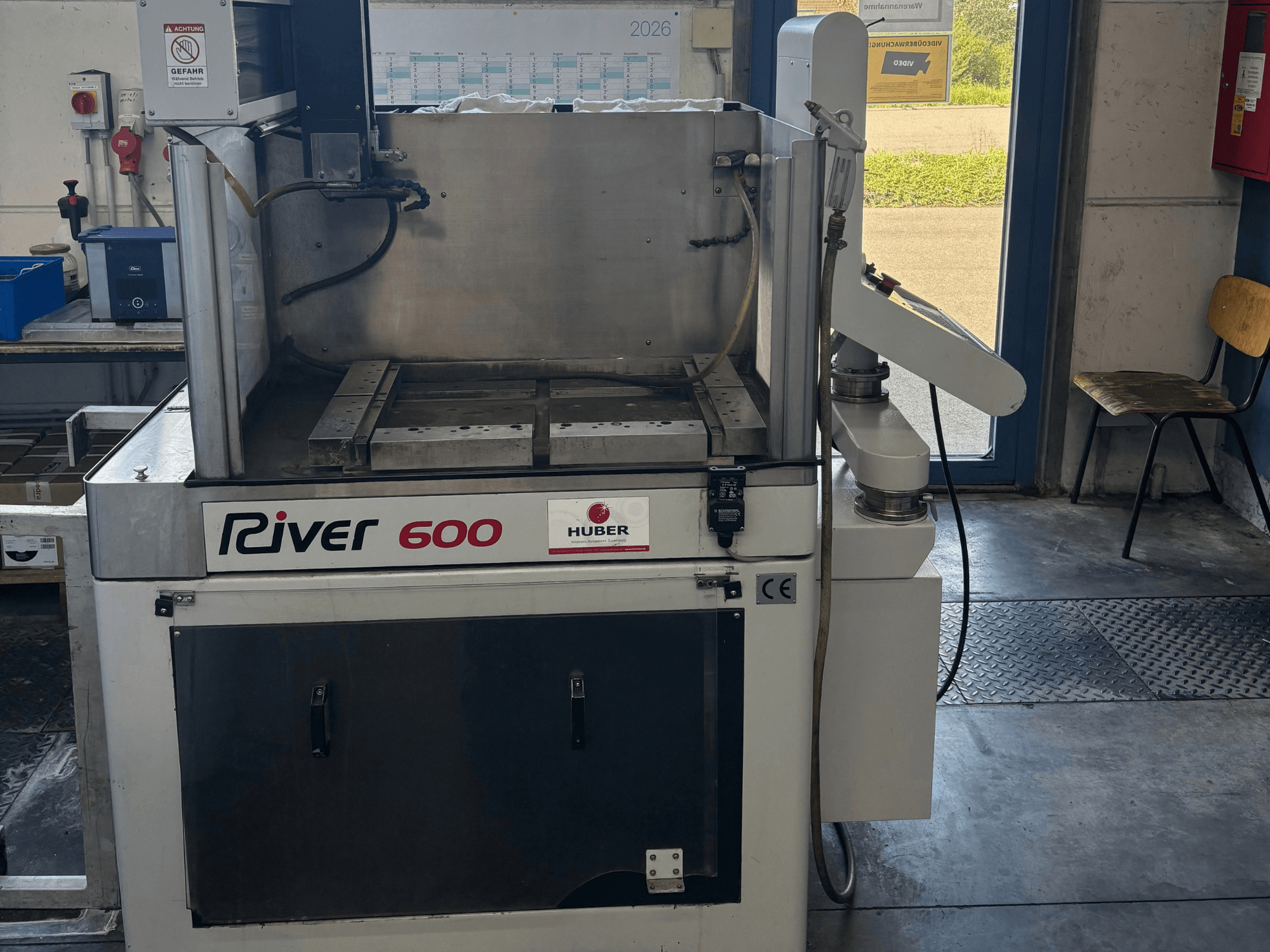 Máquina de eletroerosão por penetração HUBER River 600 CNC, vista frontal, apresentando uma câmara de trabalho parcialmente aberta e o painel de controlo.
