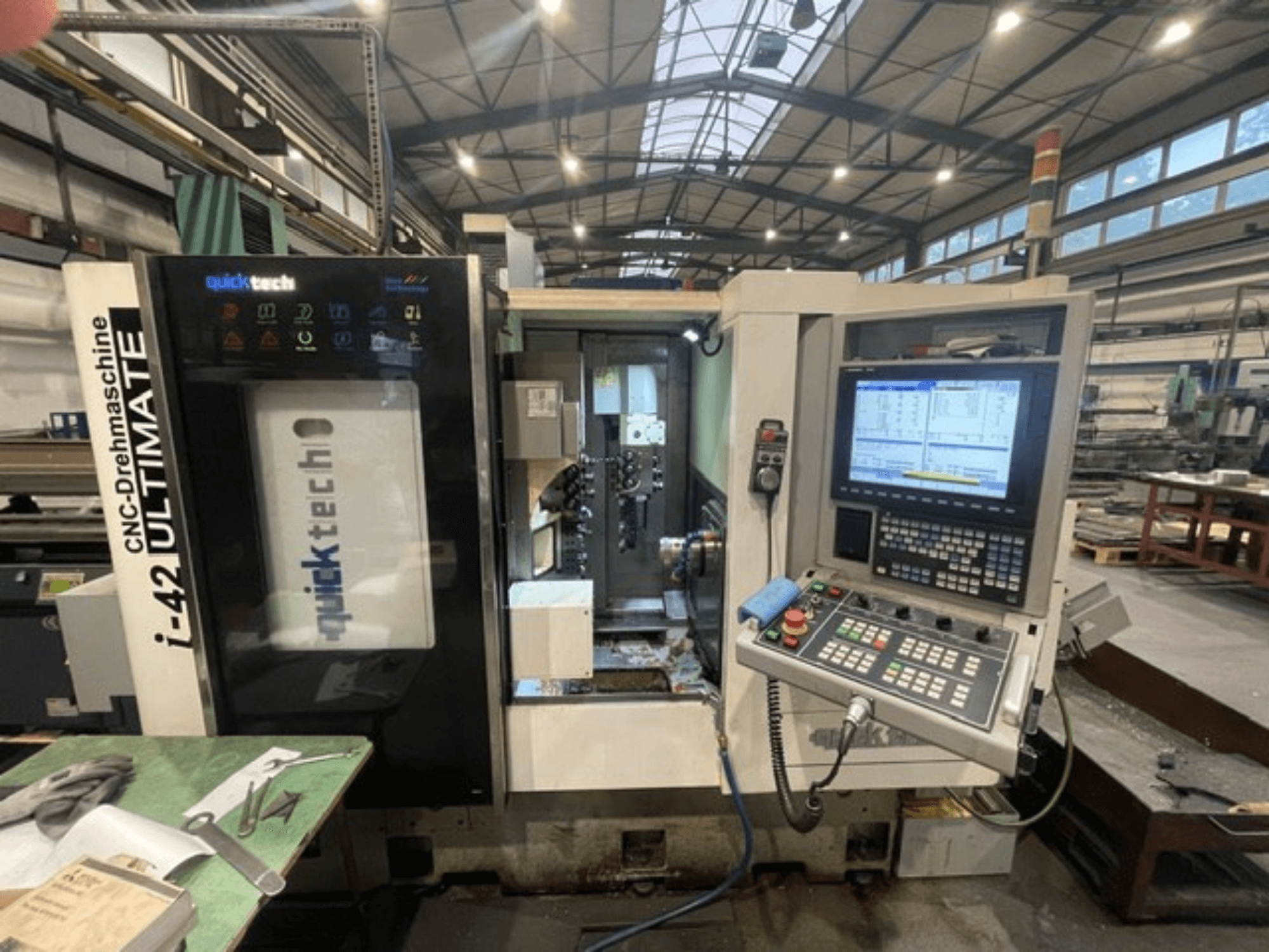 Quick-Tech I-42U Swiss Type Turning Machine, vista frontal, mostrando o painel de controlo e a interface CNC numa oficina.