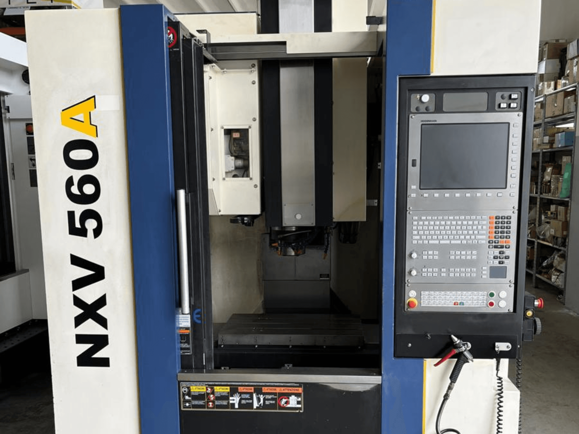 Máquina CNC NXV 560A vista de frente, com um painel de controlo com botões e um visor digital.