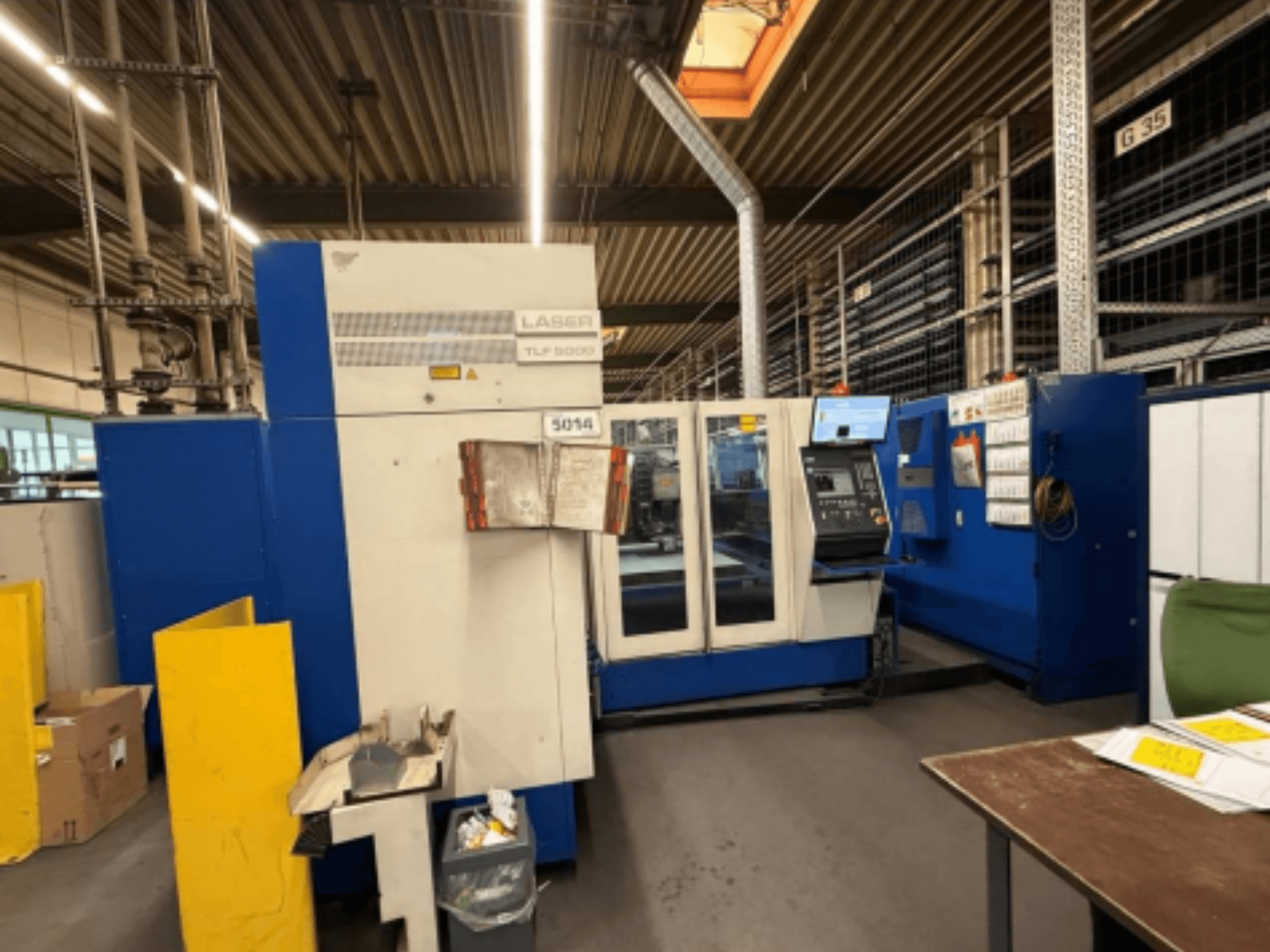 Vista frontal da máquina de corte a laser TRUMPF Trumatic L 3050 CO2, mostrando o painel de controlo e as caraterísticas operacionais numa oficina.