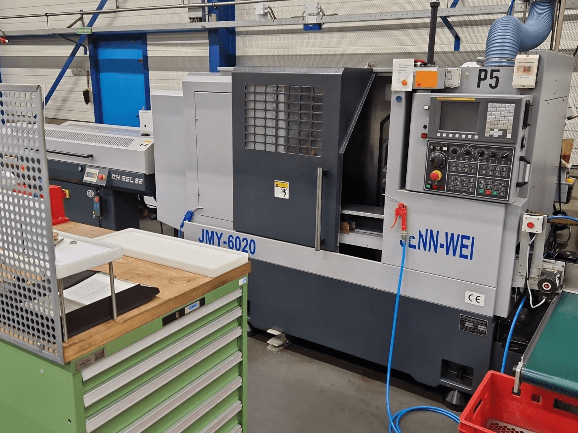 Máquina de torno CNC, modelo JMY-6020 da cNN-WEI, vista de frente. Apresenta painel de controlo, paragem de emergência e linha de refrigeração.