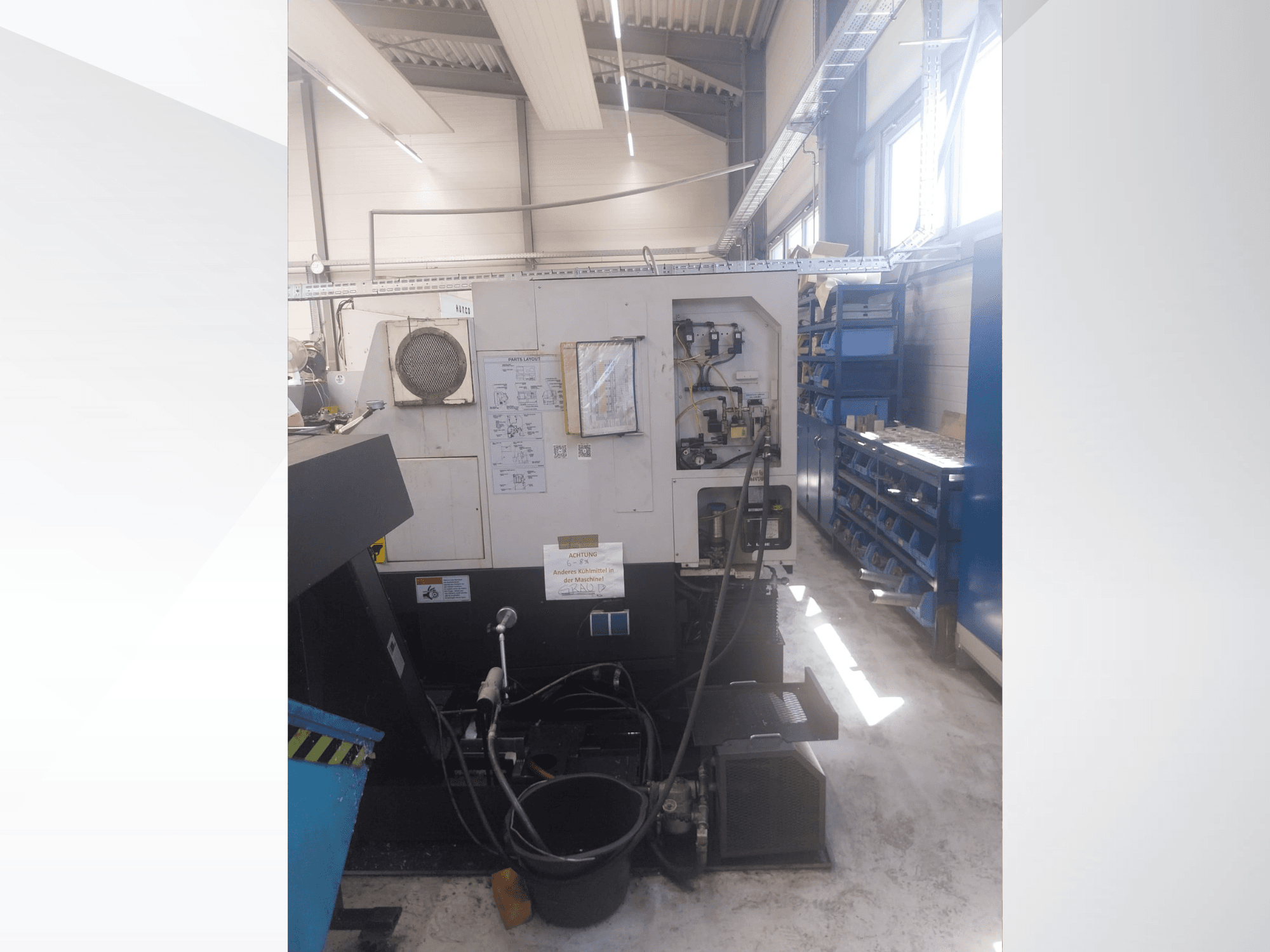 Mazak QUICK TURN NEXUS 200 MS, vista lateral que mostra o painel de controlo, as mangueiras e a área das ferramentas num ambiente de oficina.