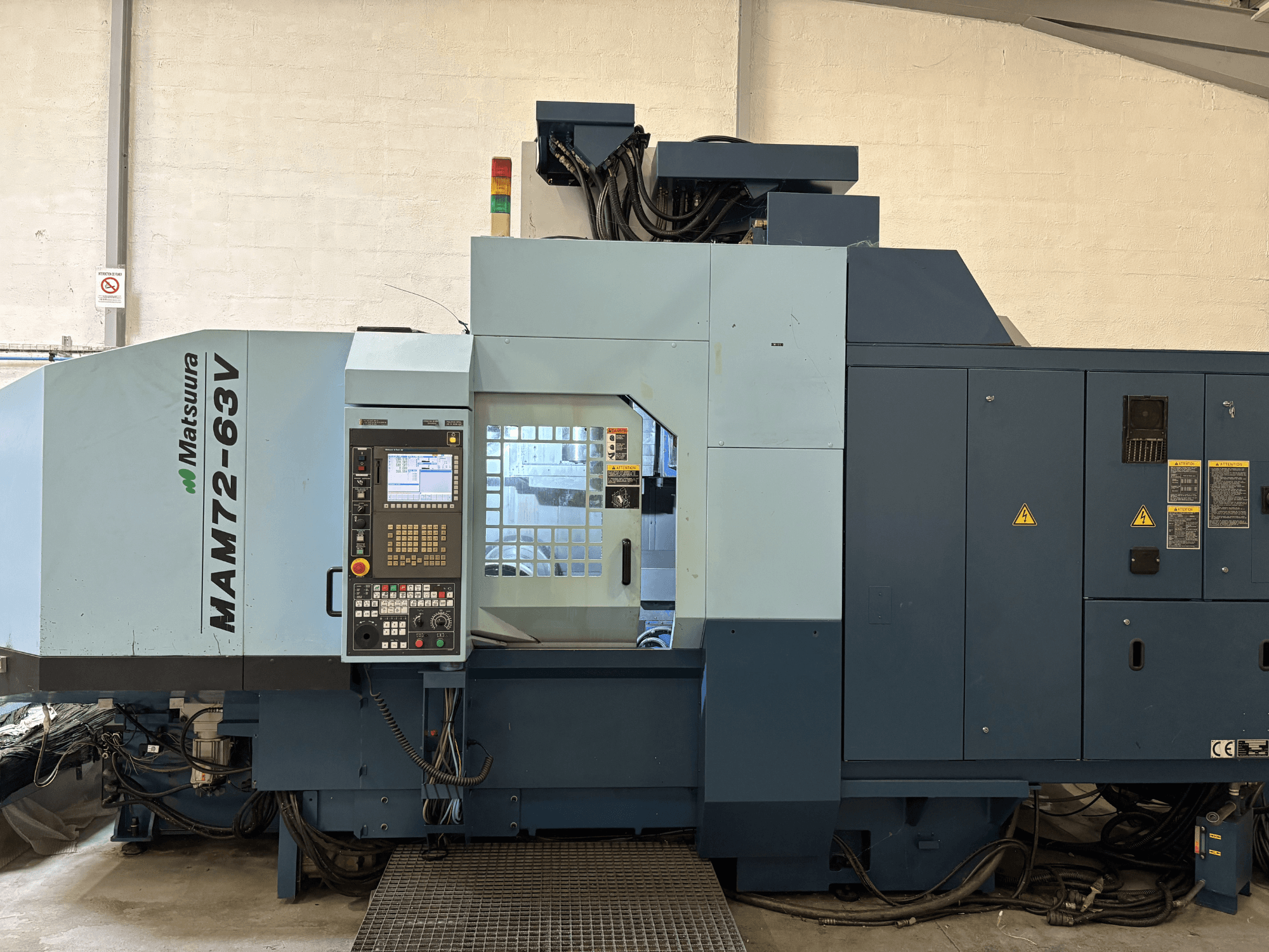 Centro de maquinação vertical Matsuura MAM 72-63 V, vista frontal mostrando o painel de controlo e as caraterísticas de segurança.