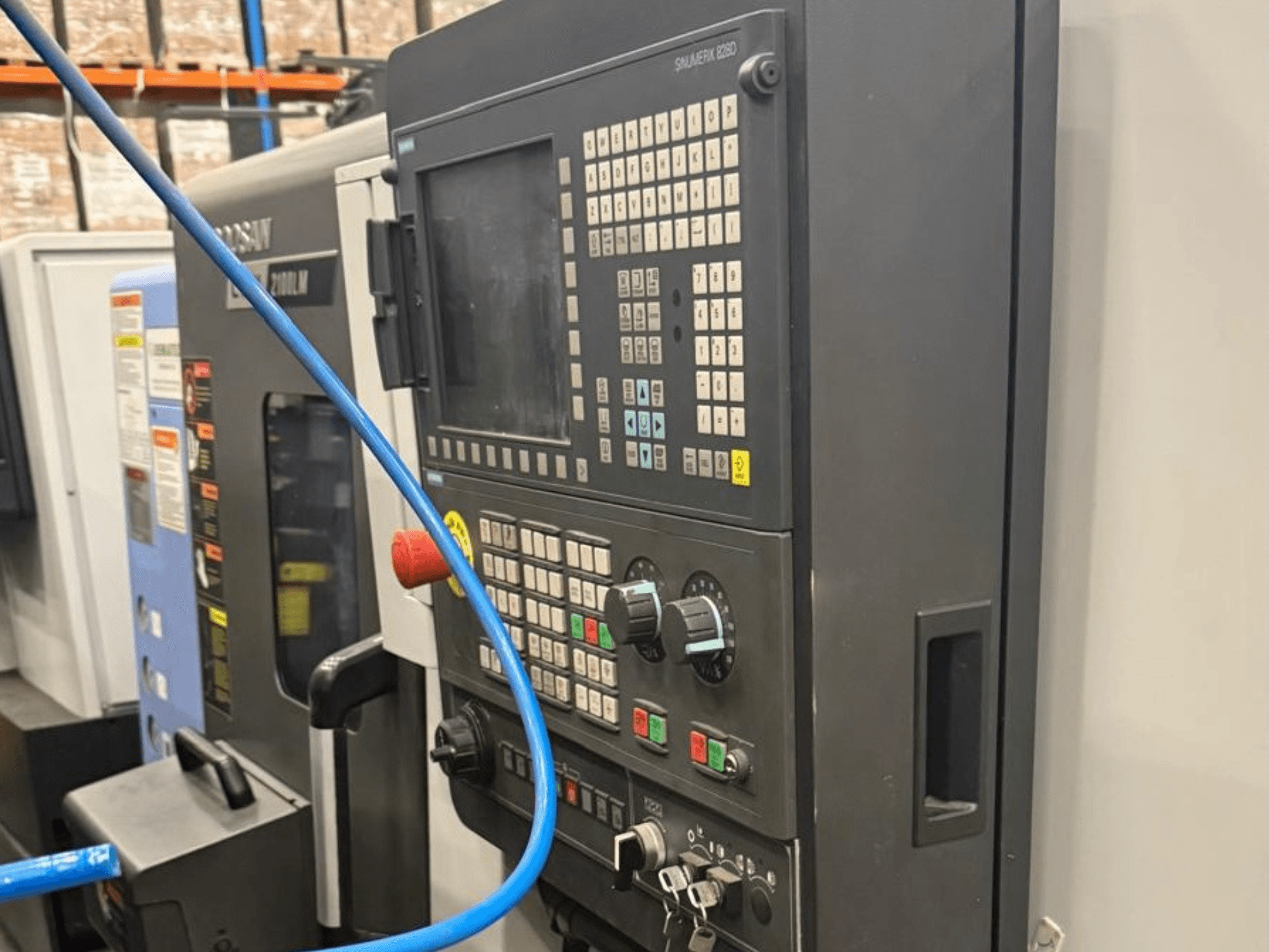 Painel de controlo de uma ferramenta de maquinagem, vista frontal, com botões e um visor digital para uma operação precisa.