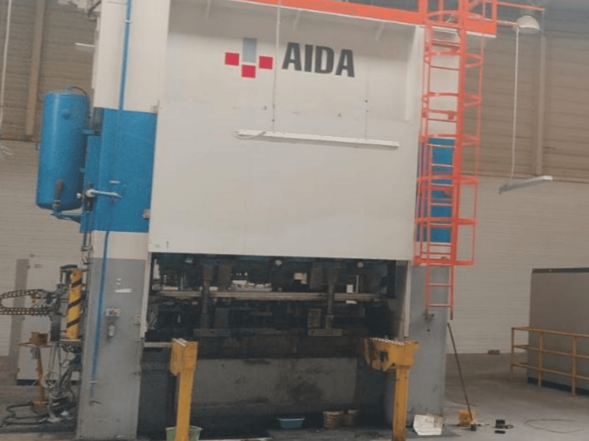 Prensa de Estampagem Mecânica AIDA 315/2MR/LD/TE3, vista frontal, mostrando os componentes hidráulicos e a escada de segurança.
