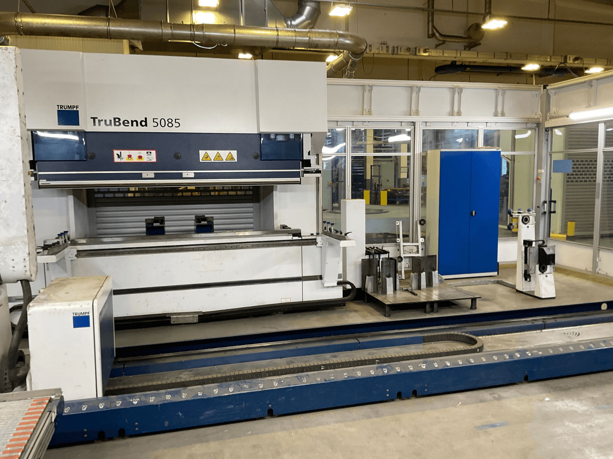 TruBend 5085 da TRUMPF, vista lateral de uma grande máquina de dobragem de metal com painel de controlo e várias ferramentas ao lado.