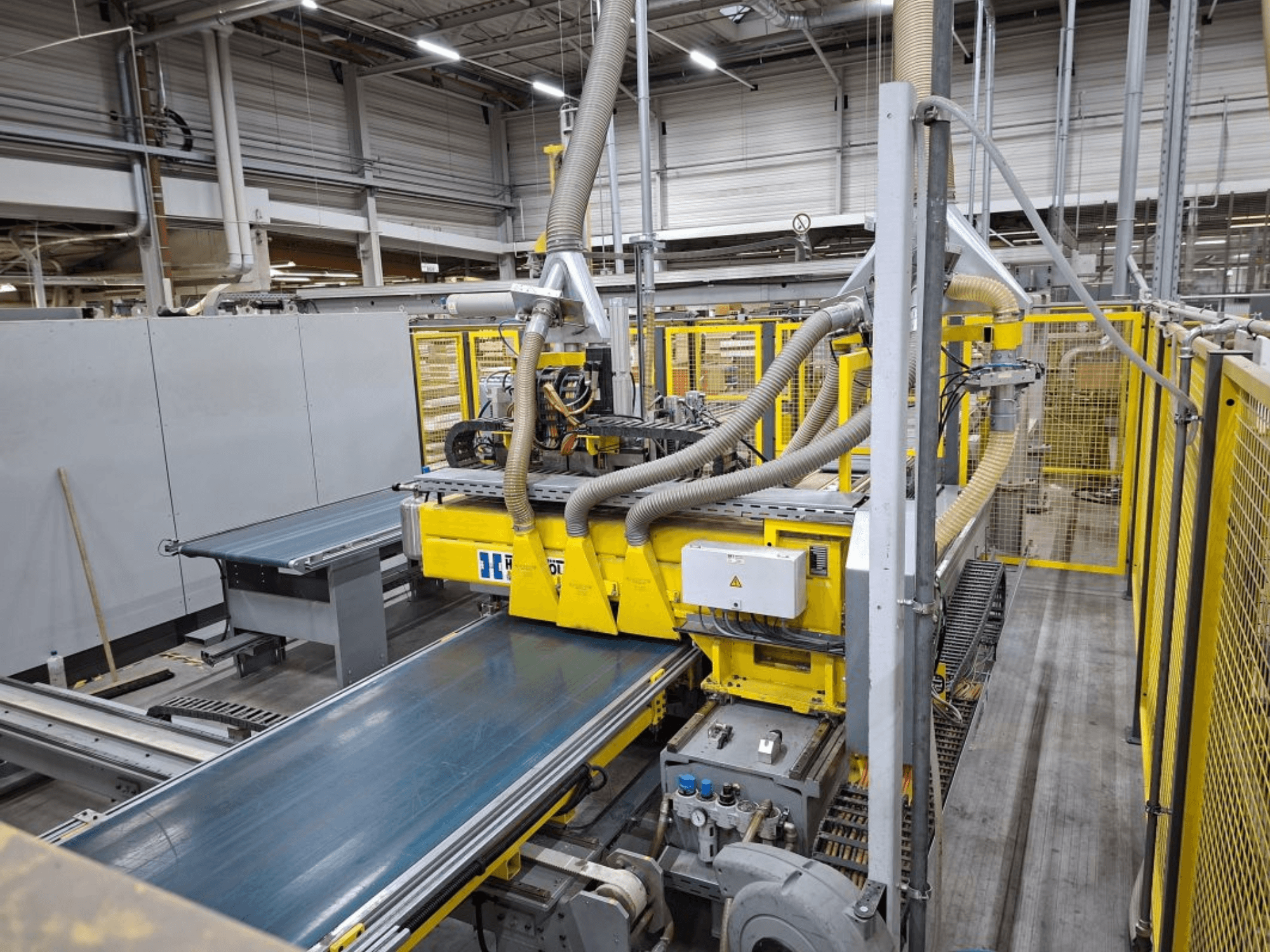 Sistema de transporte industrial a partir de uma vista lateral, com maquinaria amarela, painel de controlo e acessórios de mangueira para fabrico.