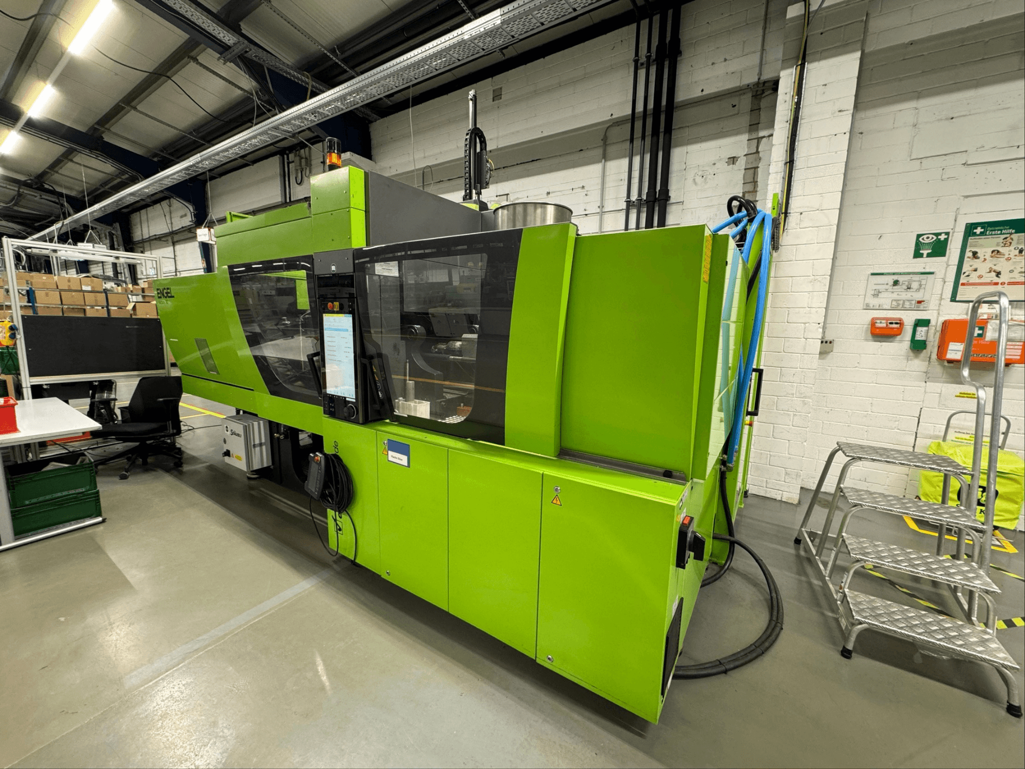 Máquina de moldagem por injeção hidráulica Engel Victory 200/90 tech, na cor verde, vista lateral que mostra o painel de controlo frontal e a área circundante.
