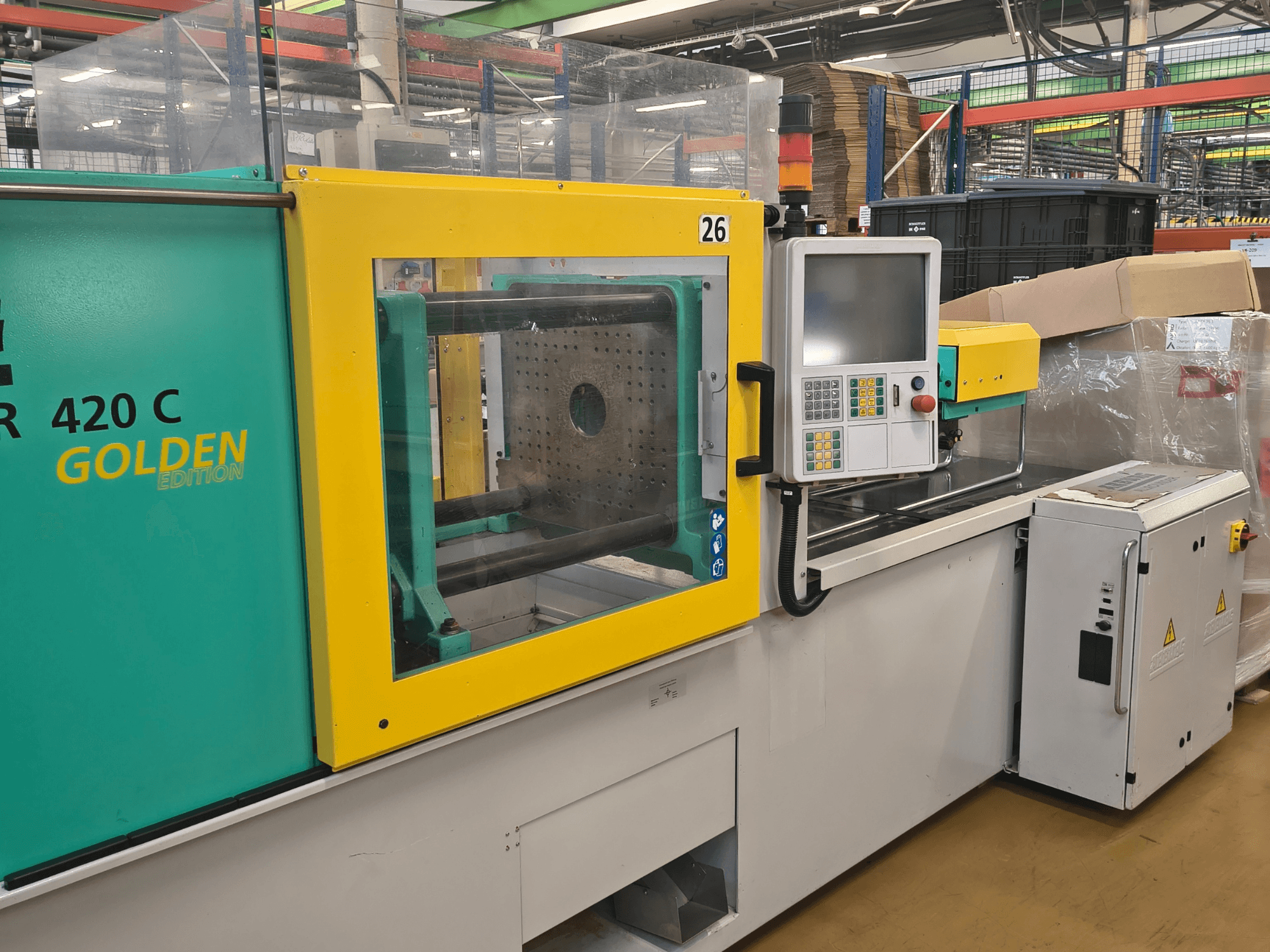 Máquina de moldagem por injeção ARBURG 420 C Golden Edition, vista frontal; painel de comando, resguardo de segurança transparente e área de trabalho circundante.