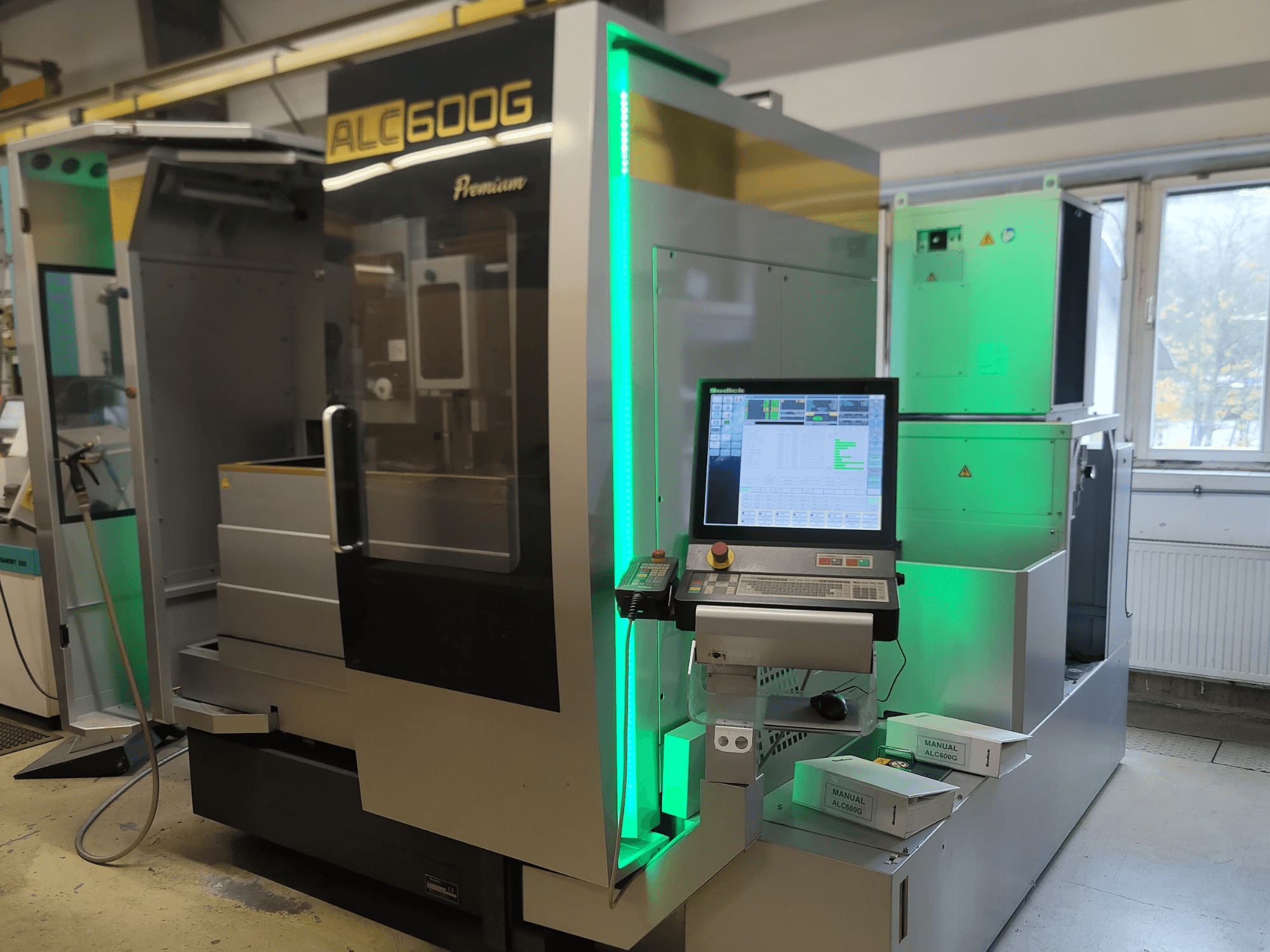 Sodick ALC600G Premium Wire EDM, vista frontal, mostrando o painel de controlo e detalhes exteriores iluminados.