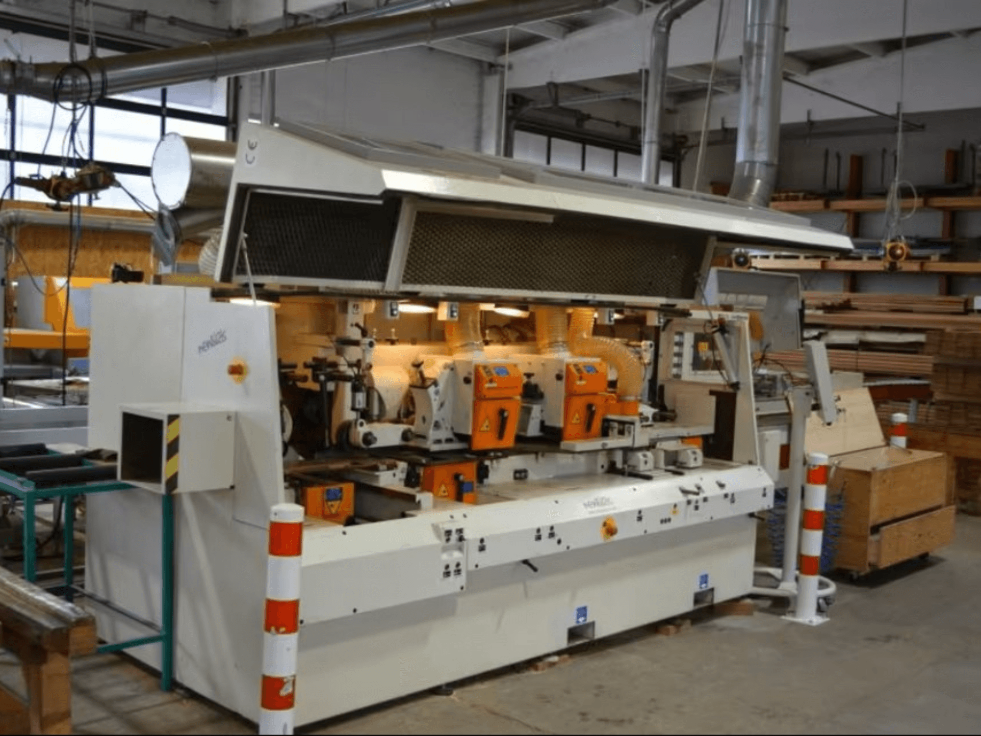 Máquina de processamento de madeira PENIGAS, vista frontal, com duas cabeças de corte laranja e sistema de extração de poeiras numa oficina.