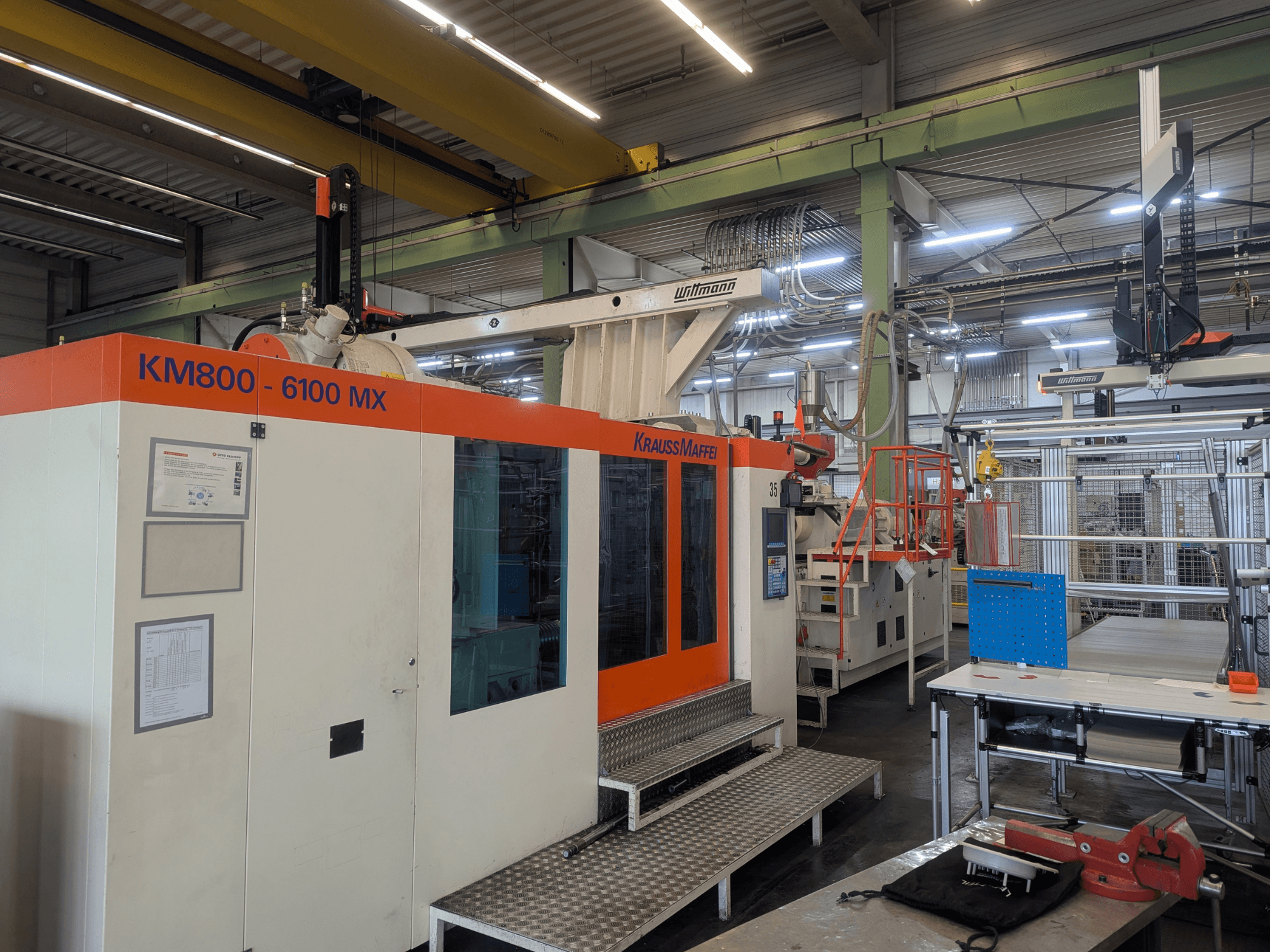 Máquina de moldagem por injeção hidráulica Krauss Maffei KM 800-6100MX, vista frontal, mostrando o painel de controlo e a configuração industrial.