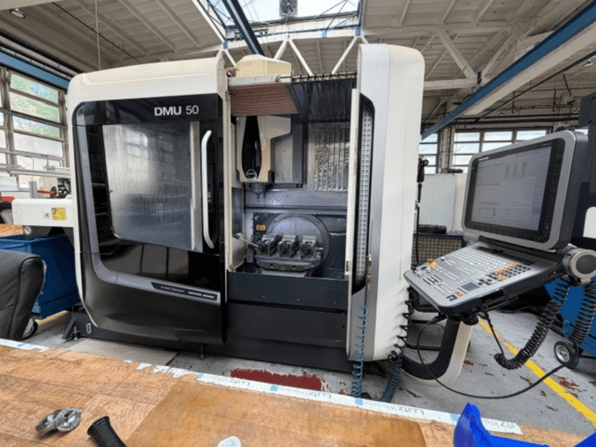 Centro de maquinagem vertical DMG MORI DMU 50 de 3.ª geração, visto de frente, com a porta aberta, o painel de controlo CNC visível e a área de trabalho no interior.