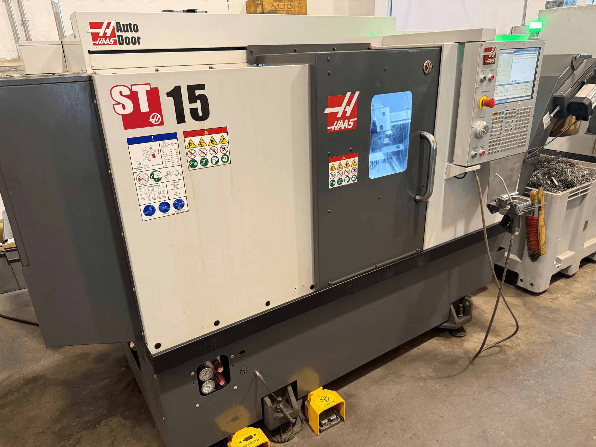 Torno horizontal HAAS ST 15, vista frontal que mostra o painel de controlo, a porta automática e os indicadores técnicos visíveis.