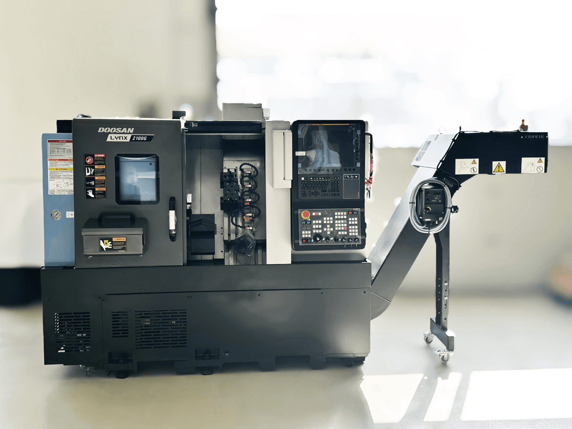 DOOSAN LYNX 2100GA Torneiro de tipo suíço em vista lateral com painel de controlo e porta-ferramentas visíveis.