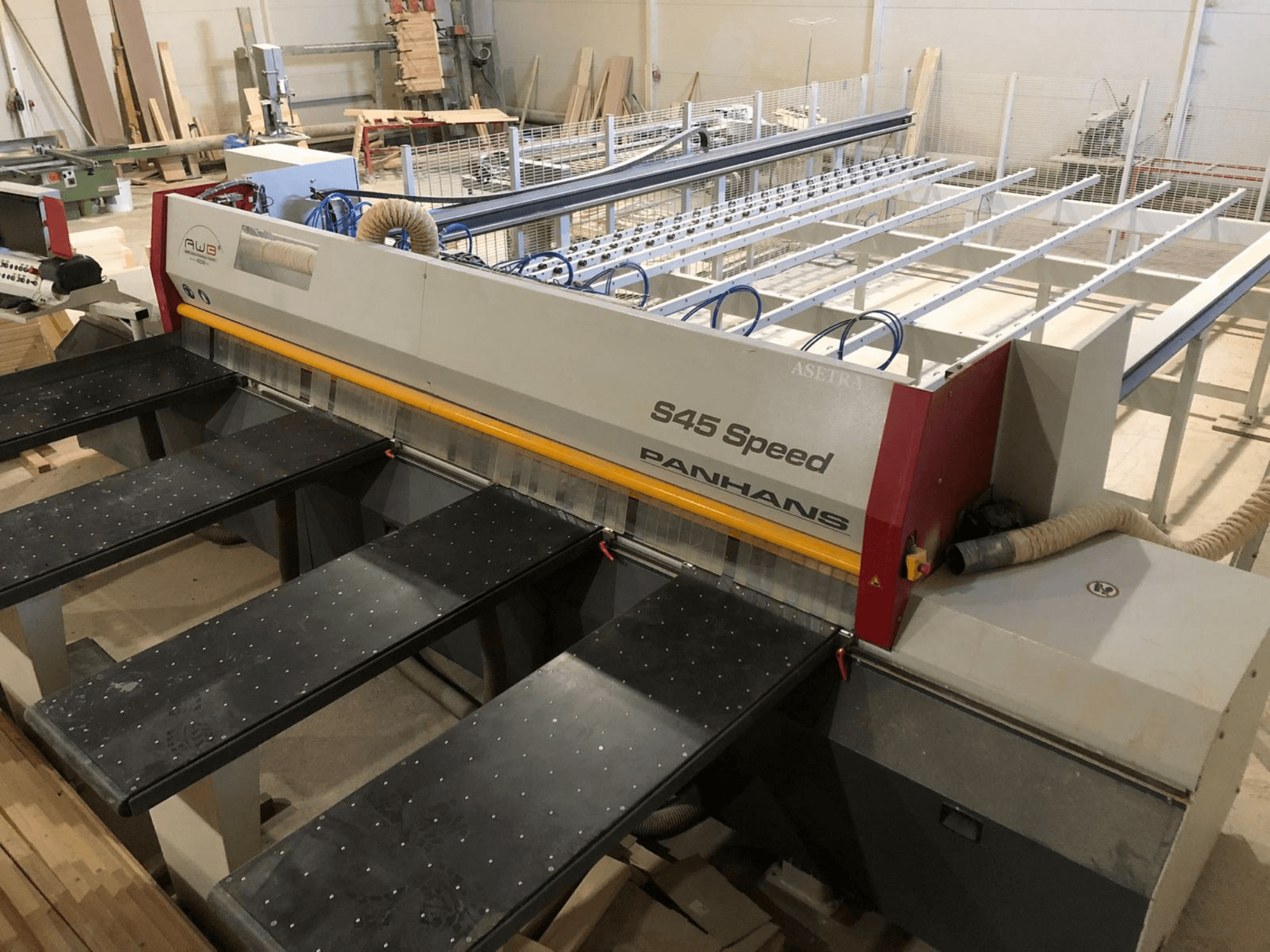 Vista lateral de uma serra de painel PANHANS S45 Speed, com uma configuração de cinco mesas e um painel de controlo visível com extração de poeiras.