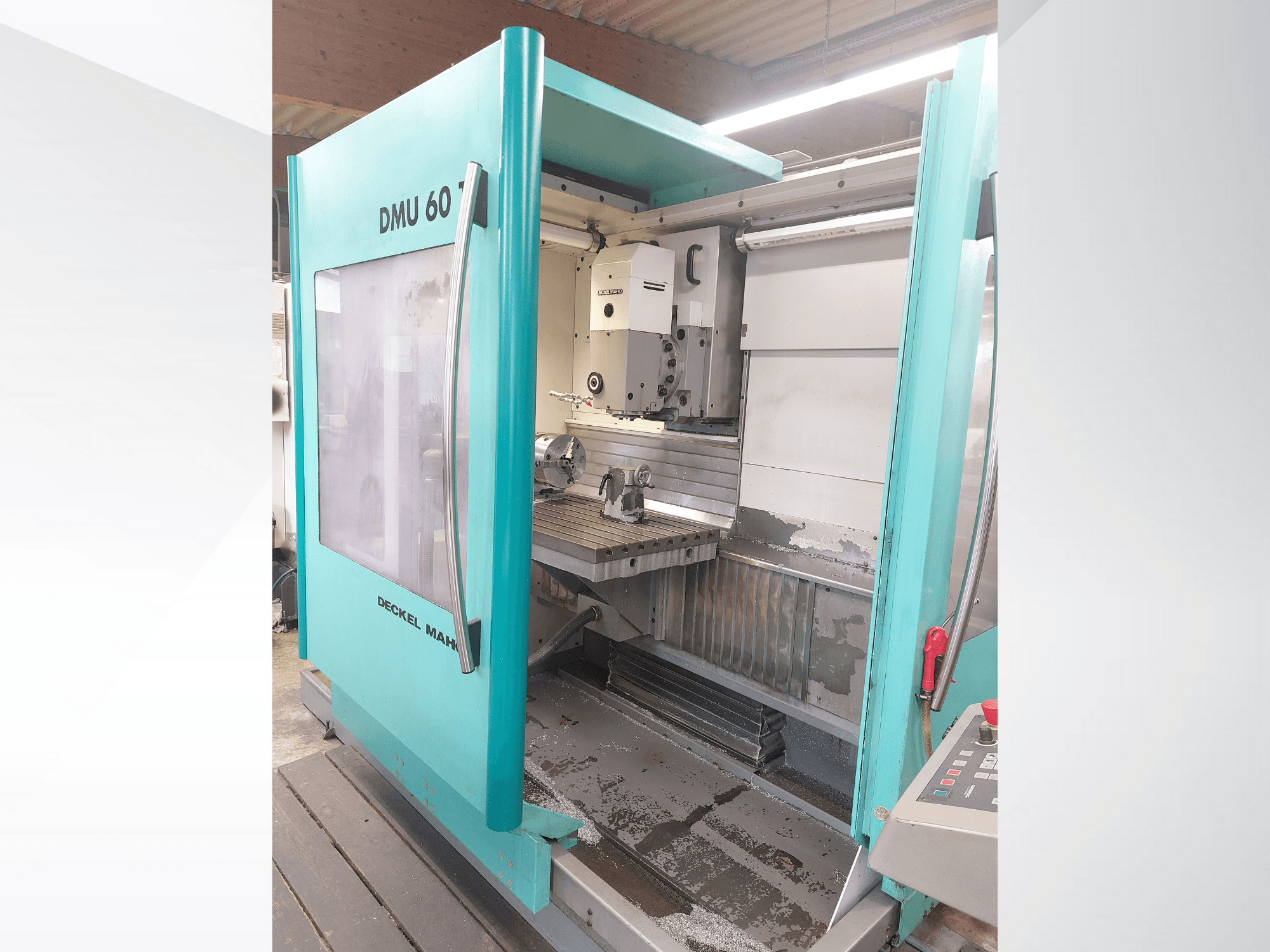 Máquina CNC Deckel MAHO DMU 60, vista frontal. Apresenta um painel de controlo visível e uma mesa de fresagem com uma configuração de peça de trabalho.