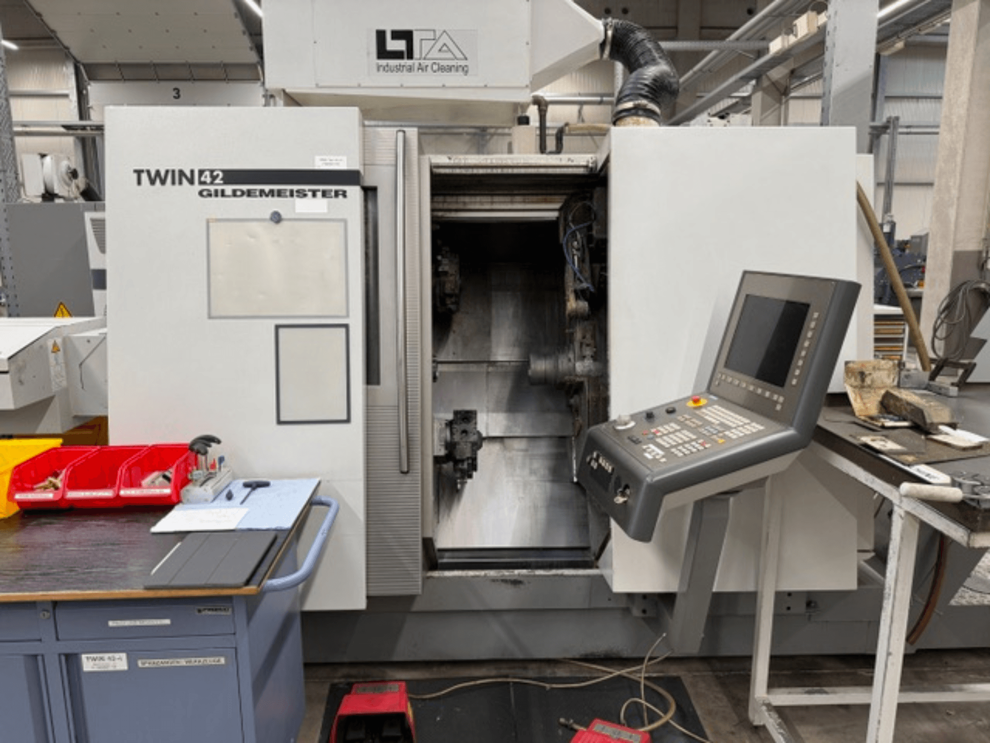 Torno horizontal Gildemeister TWIN 42, vista frontal que mostra o painel de controlo e a área de trabalho aberta.