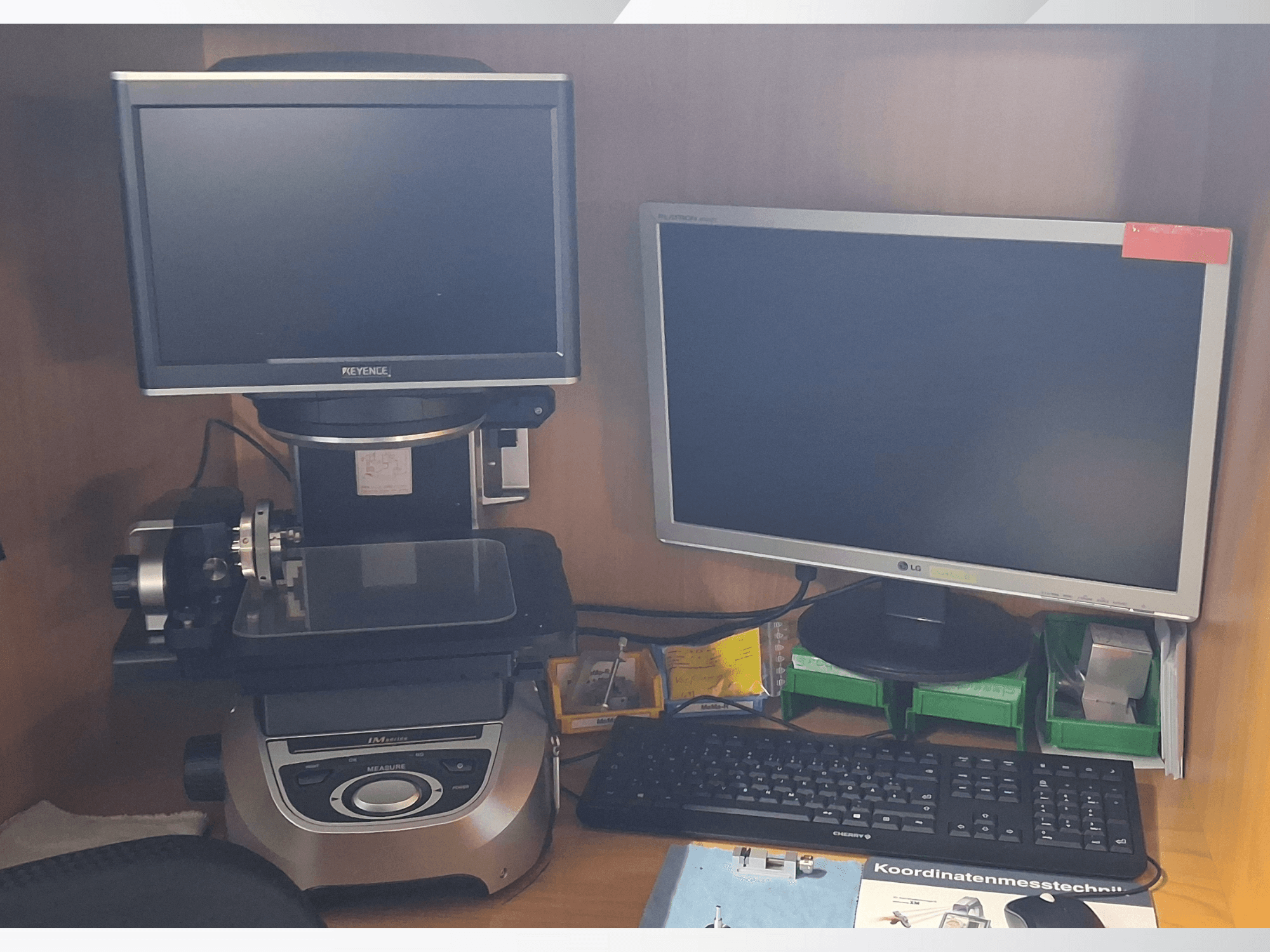 Sistema de medição Keyence com dois monitores (um LG, um Keyence) e um teclado, visto de frente.