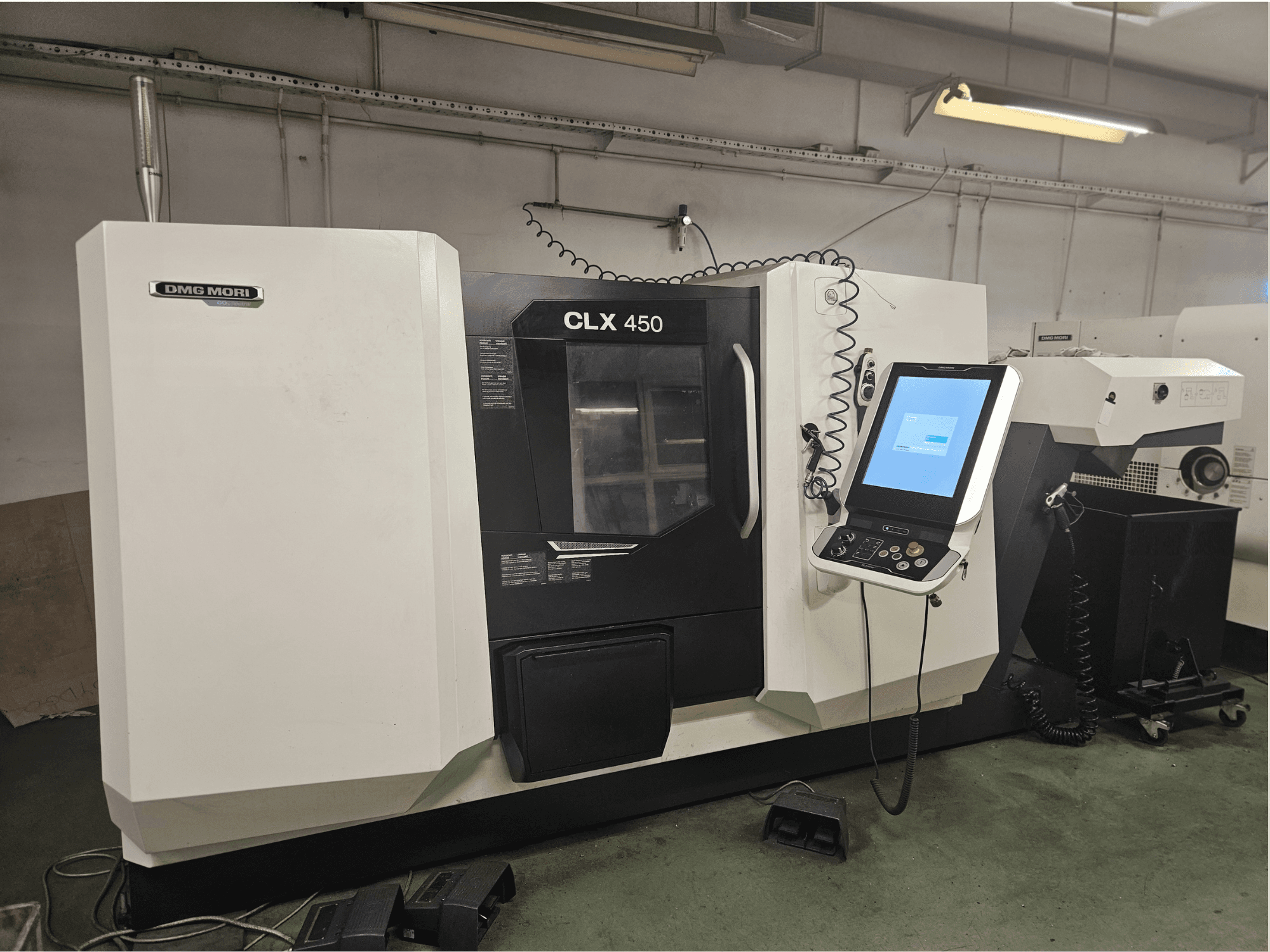 Máquina CNC DMG MORI CLX 450 em vista frontal, com painel de controlo e ecrã tátil, colocada num ambiente de oficina.