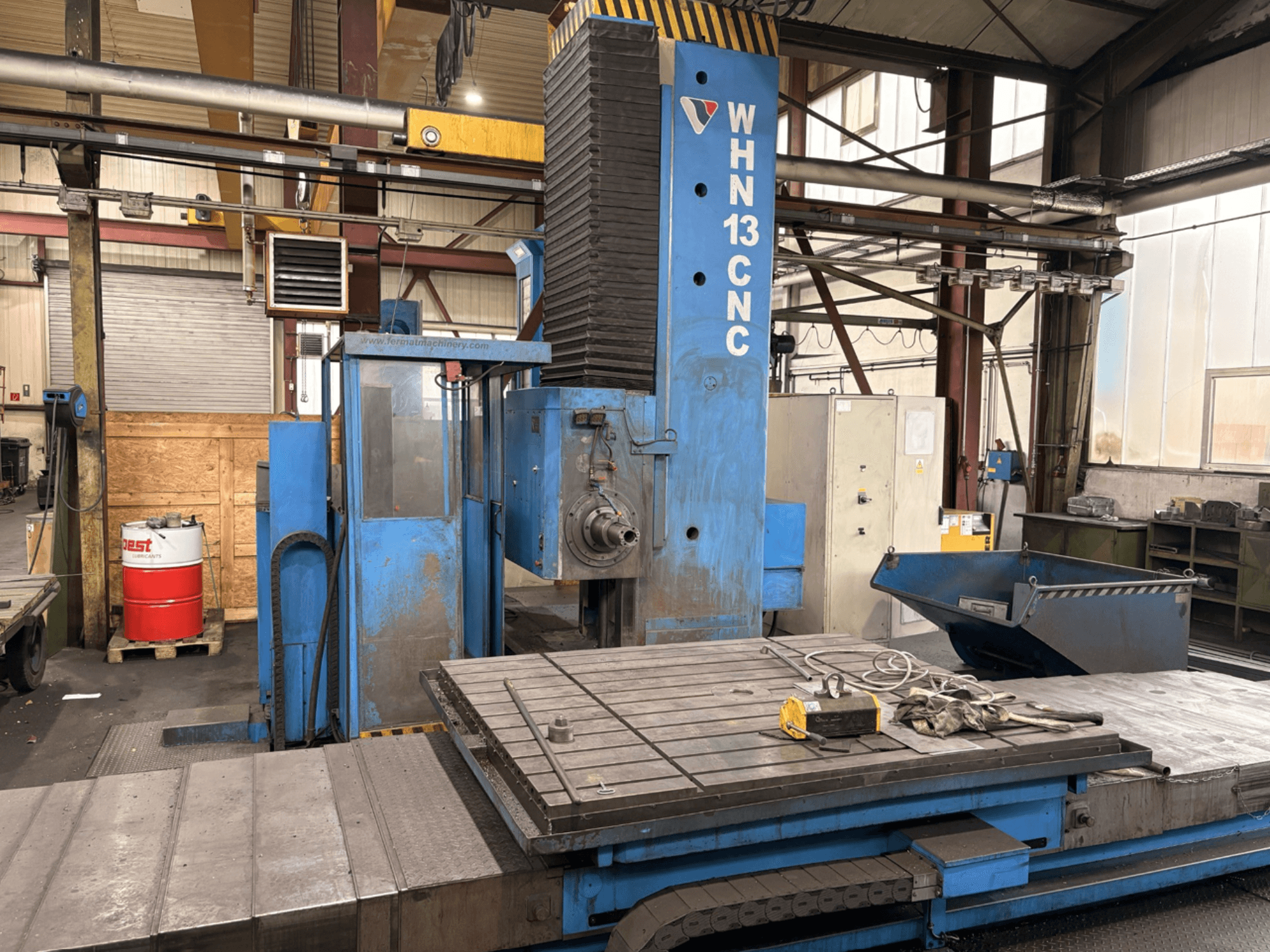 Centro de usinagem horizontal CNC FERMAT WHN 13.8, vista frontal que mostra o painel de controlo, a mesa de trabalho e detalhes do ambiente industrial.