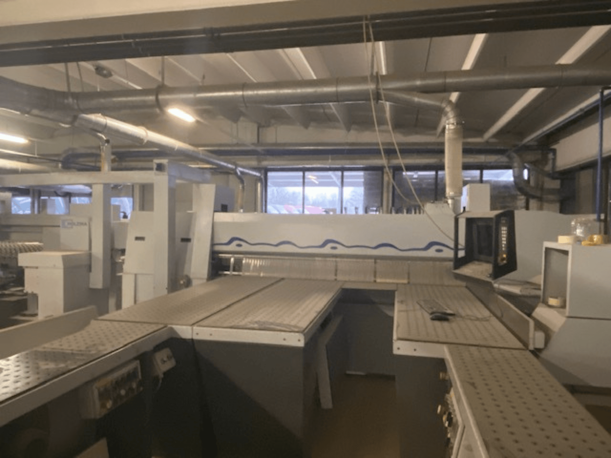 Espaço de trabalho industrial com uma configuração de máquina com painel de controlo, visto de um ângulo frontal elevado.