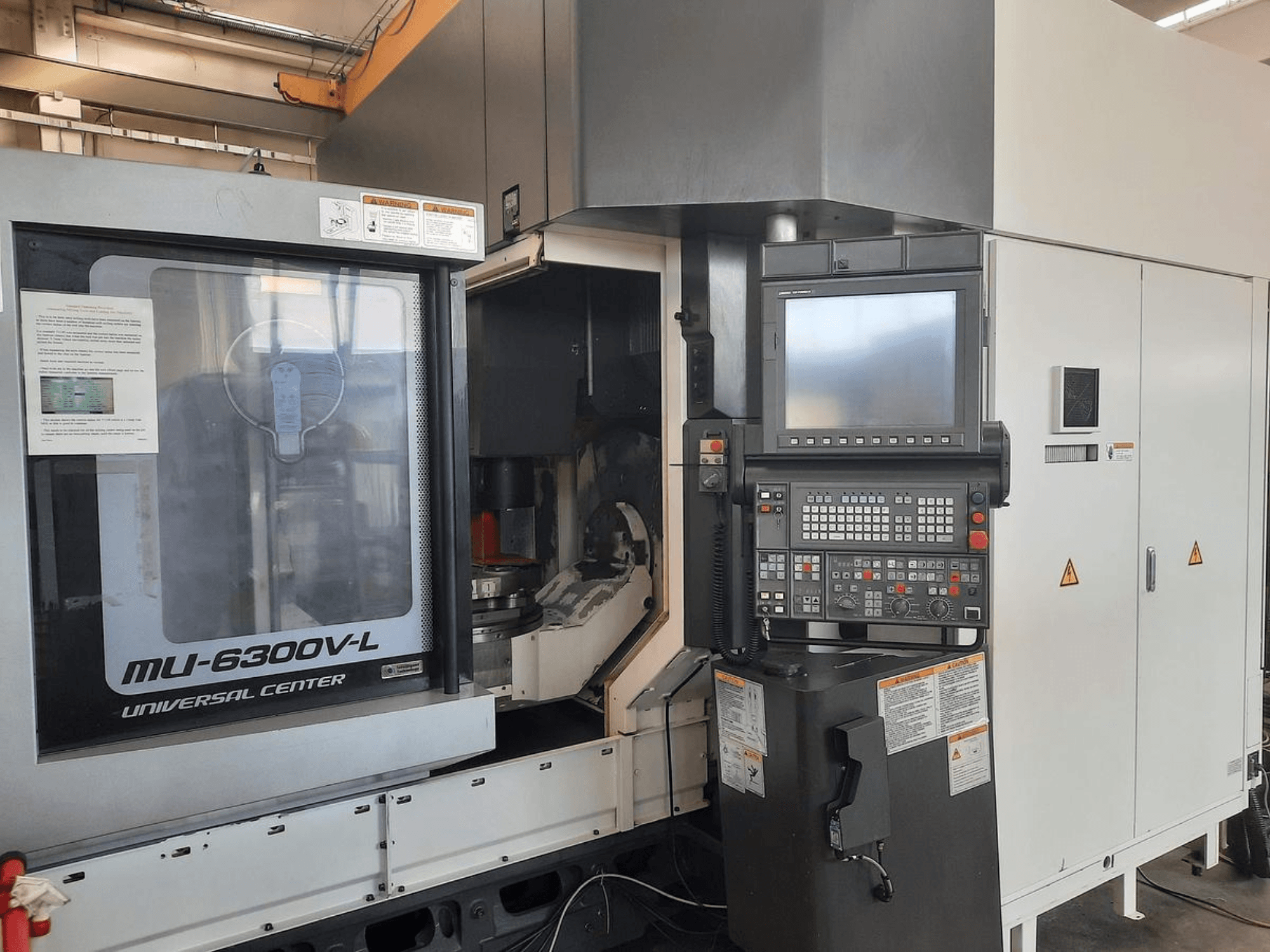 Máquina MU-6300V-L Universal Center vista de frente, com o painel de controlo, o ecrã e as instruções de funcionamento visíveis.