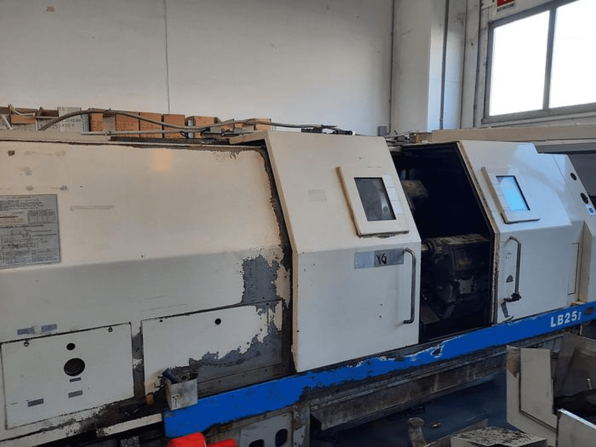 Máquina de torno LB251 usada, vista lateral mostrando o exterior desgastado, painel aberto revelando o mecanismo interior e os controlos operacionais.