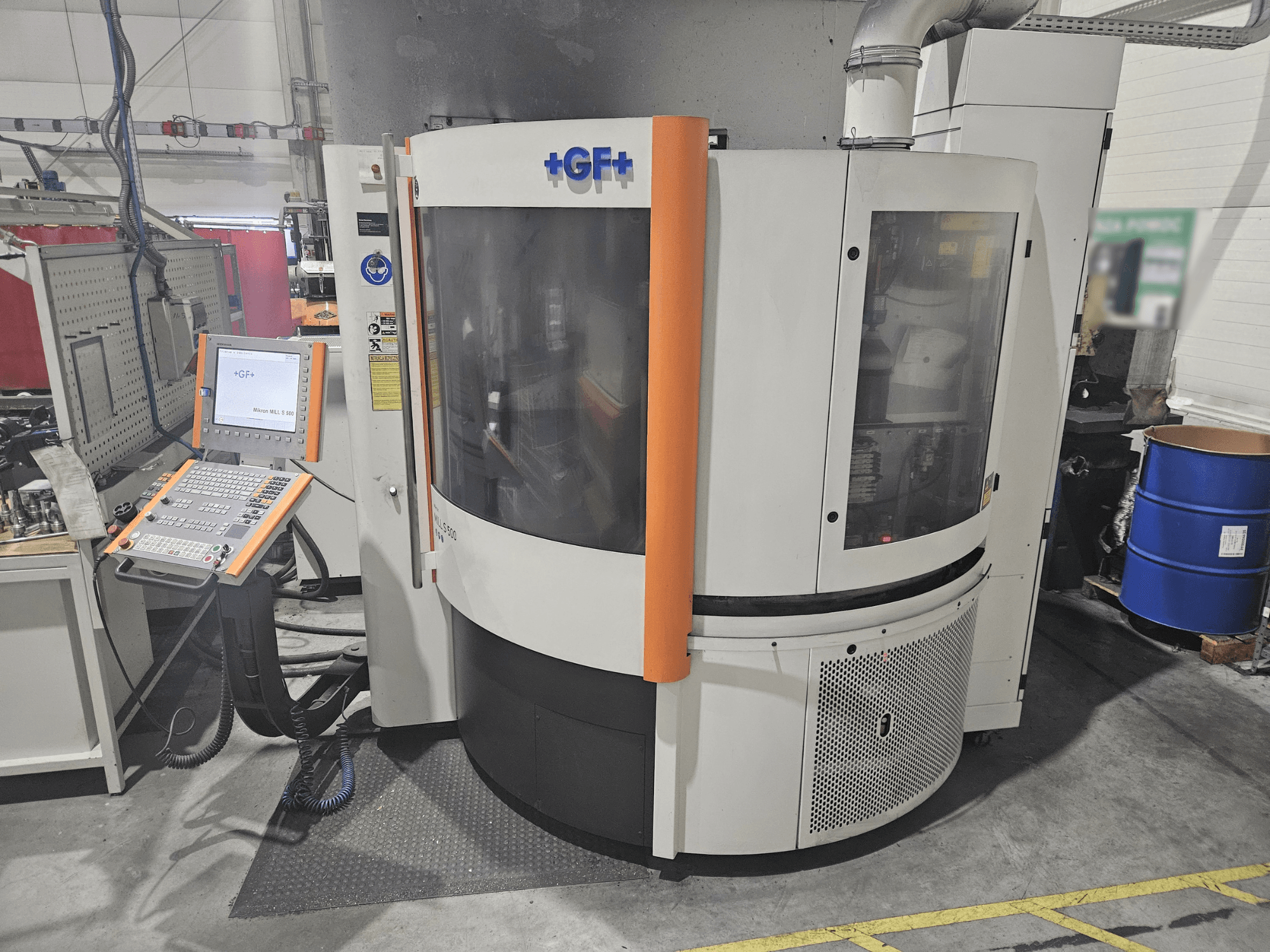 Máquina-ferramenta da GF Machining Solutions com painel de controlo, vista frontal; apresenta um painel transparente, detalhes em laranja e configuração industrial.