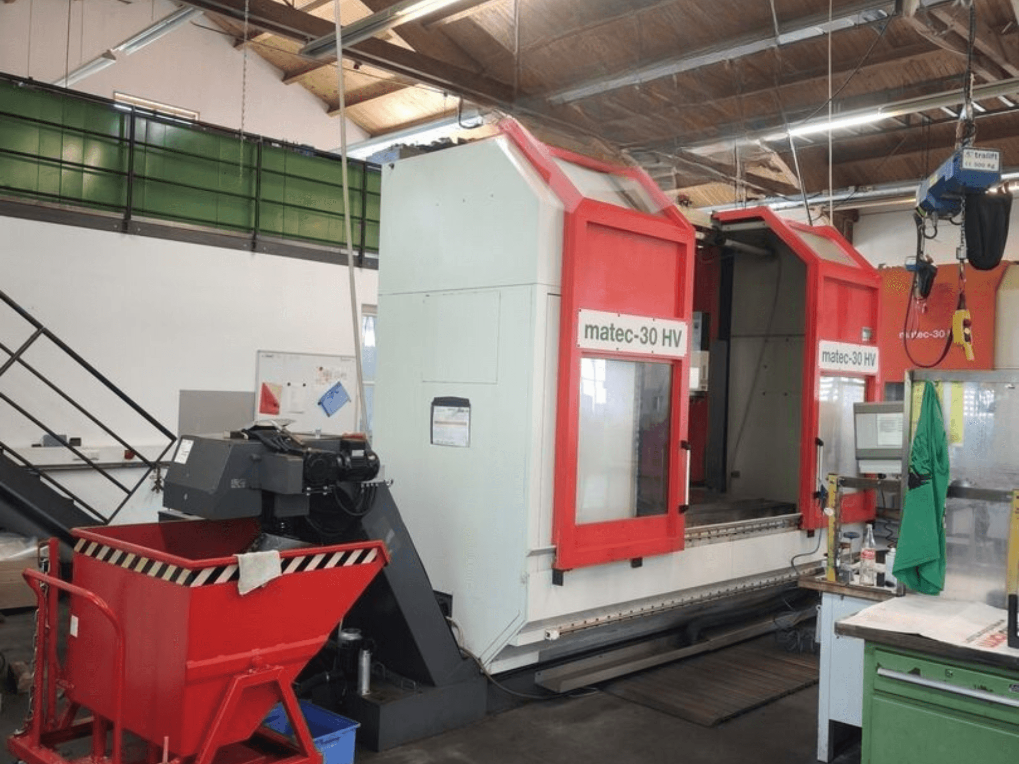 Centro de maquinagem universal Matec HV30, nas cores vermelho e branco, numa oficina; vista lateral que mostra a sua ampla área de trabalho e os seus comandos.