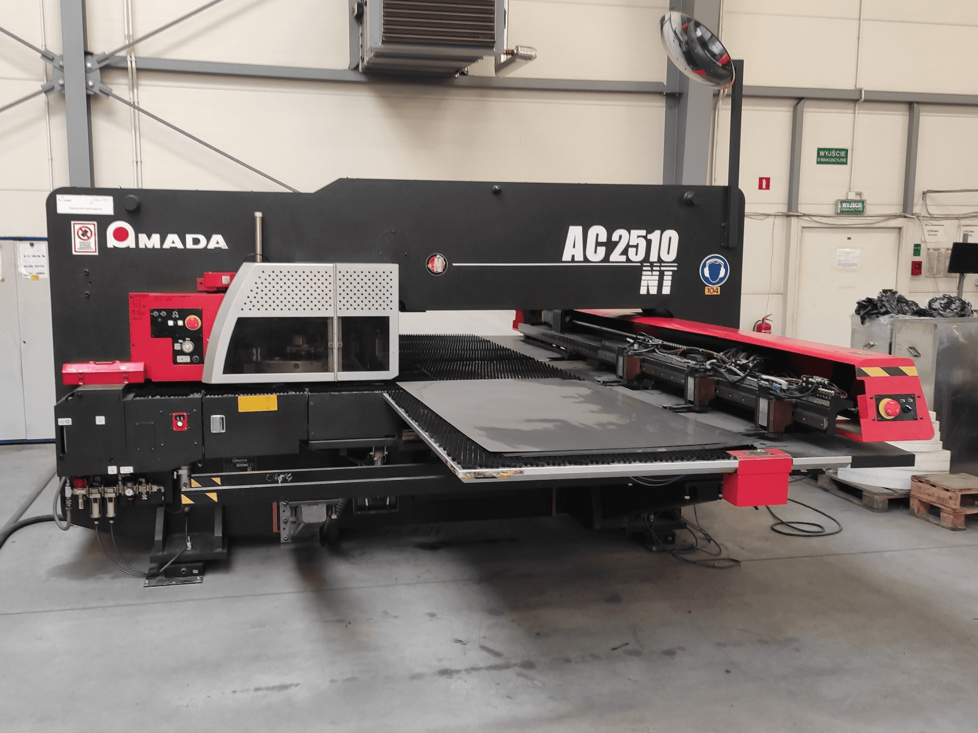 Puncionadora CNC Amada AC2510 NT, vista frontal, com painel de controlo e área de carregamento de folhas.