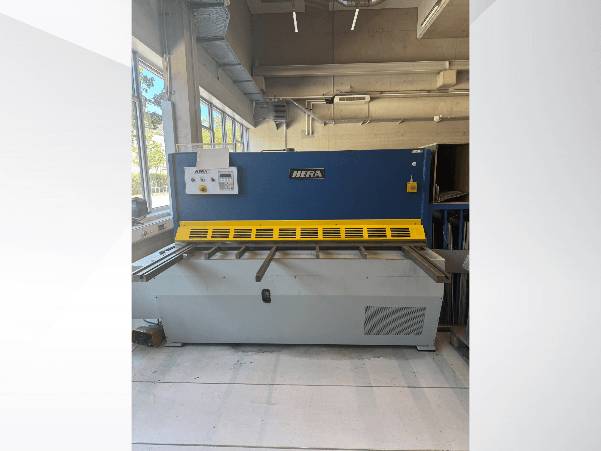 Cisalhadora hidráulica HERA TS 2000x6 vista de frente, com um design azul e amarelo, incluindo o painel de controlo e a base de corte.