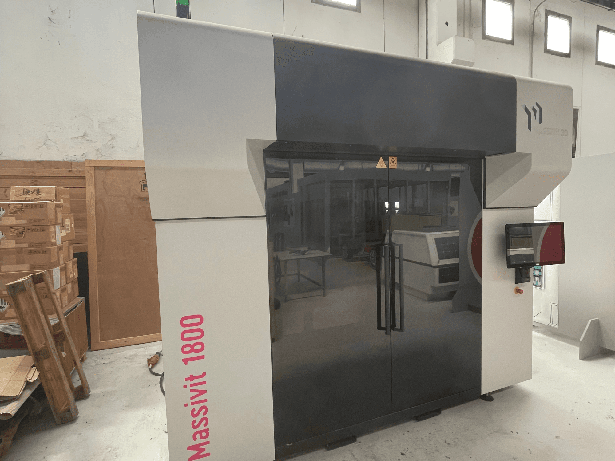 A impressora 3D de plástico MASSIVIT Massivit 1800, vista de perfil, com um ecrã tátil e um design elegante em preto e branco.