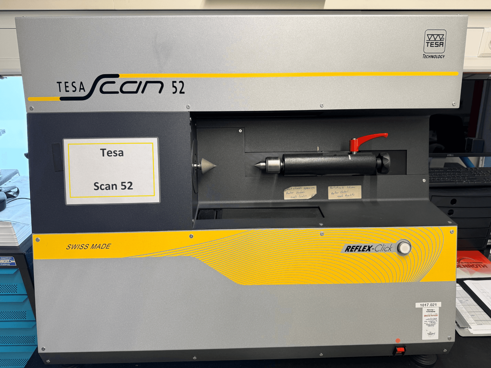 Vista frontal da máquina de medição ótica TESA Scan 52, com uma sonda preta, a etiqueta «Swiss made» e a tecnologia Reflex-Click.