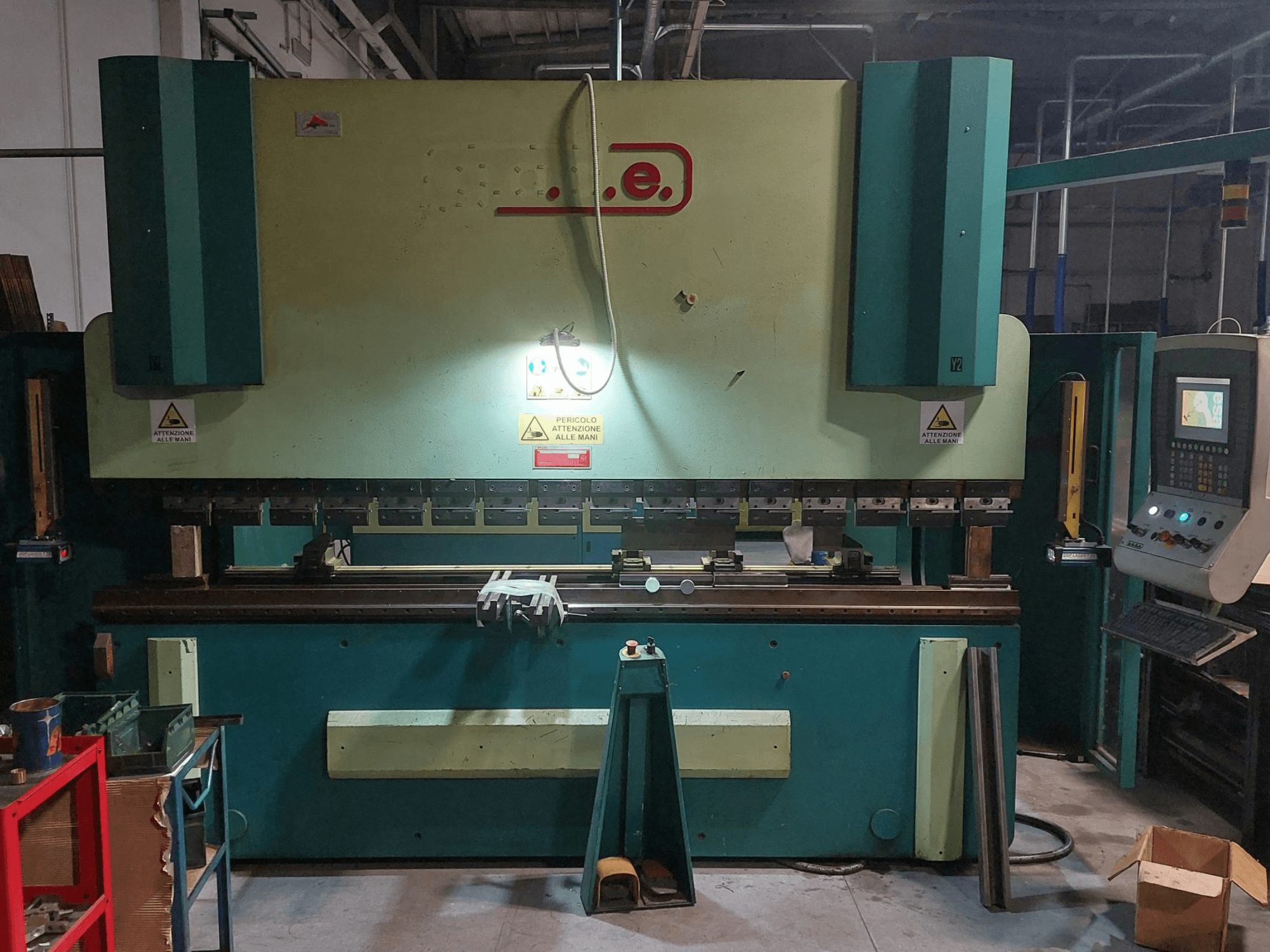 Vista frontal da prensa-dobra Gade PS-C 3120, com o painel de controlo, os sinais de segurança e a área de trabalho com ferramentas e materiais.