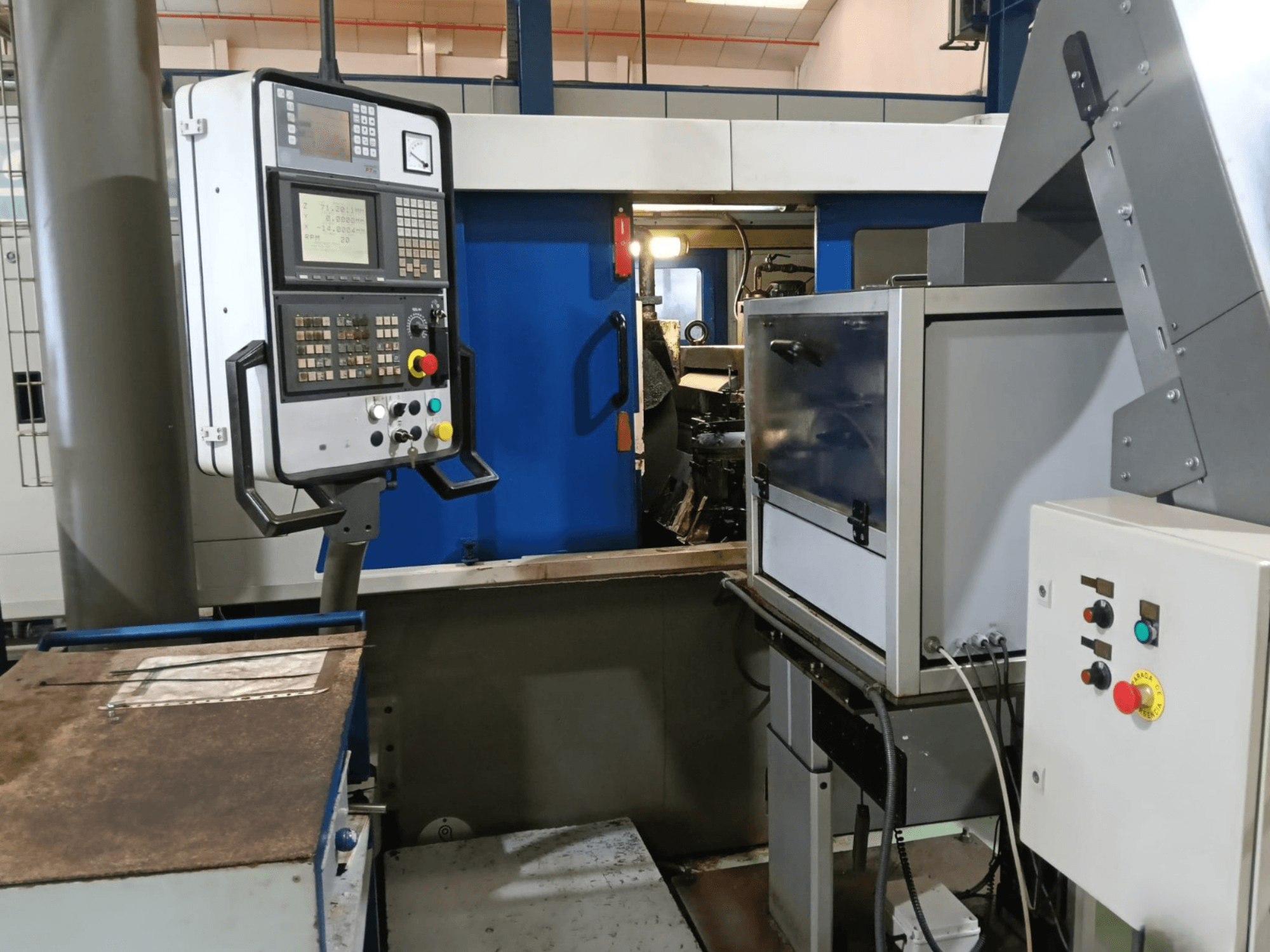 Painel de controlo e maquinaria da máquina de retificação sem centros DANOBAT 327 MDA, vista de lado, mostrando os botões e o visor.