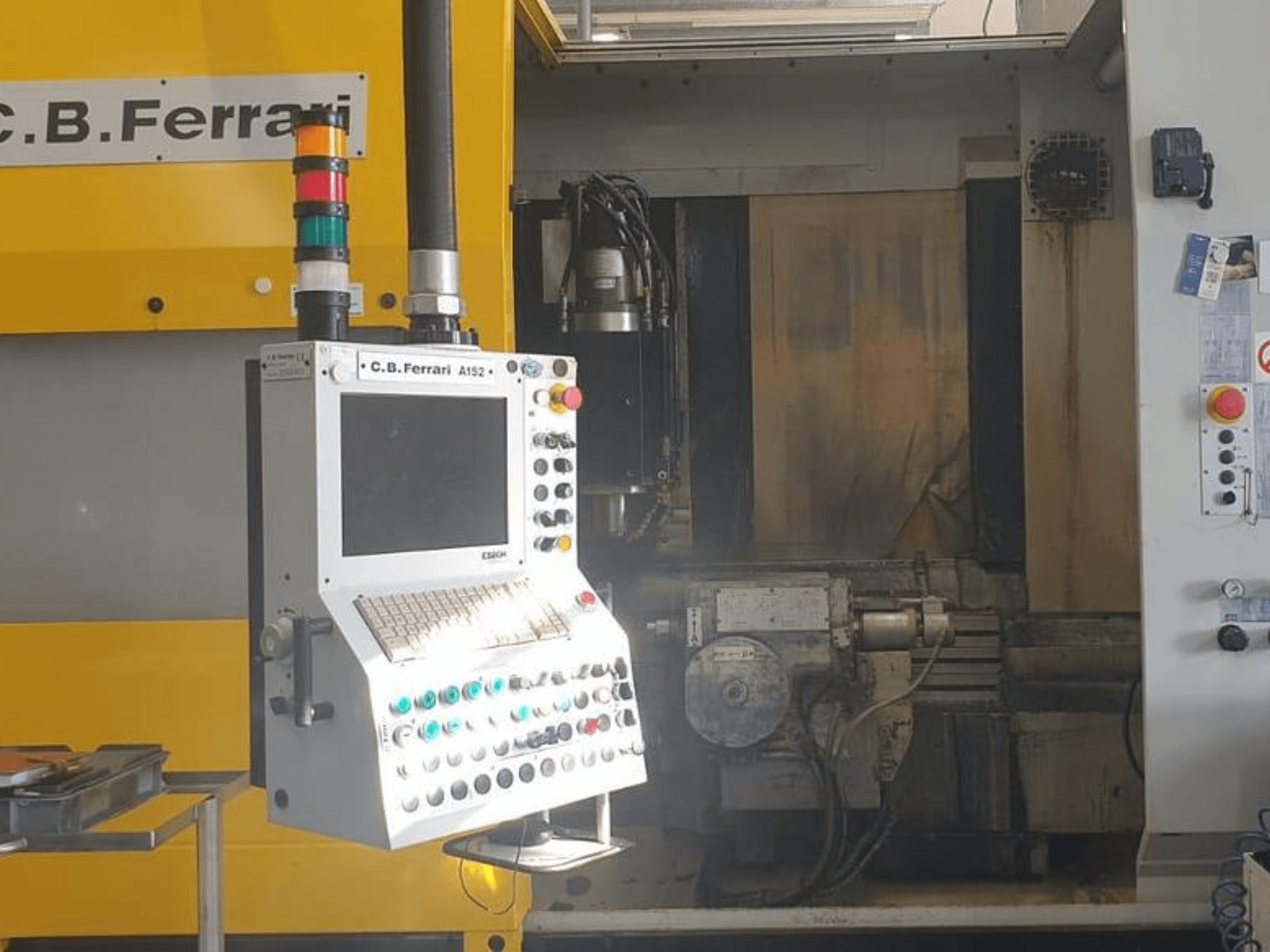 Vista frontal do Centro de Maquinação Vertical A152 da C.B. Ferrari, mostrando o painel de controlo com botões e componentes do motor na máquina.