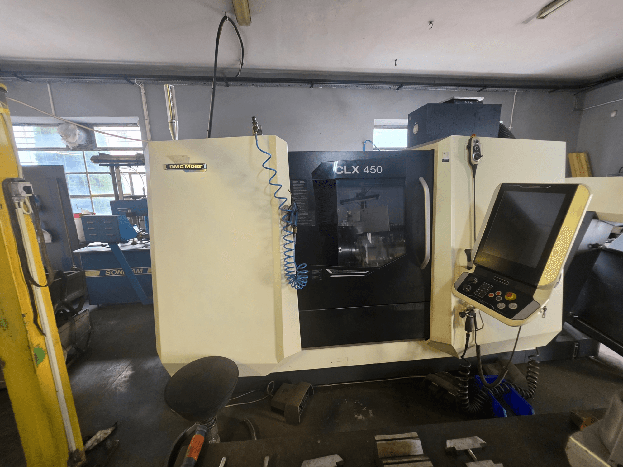 Torno horizontal DMG MORI CLX 450 V6, visto de frente, com um painel de controlo e a marca visível.