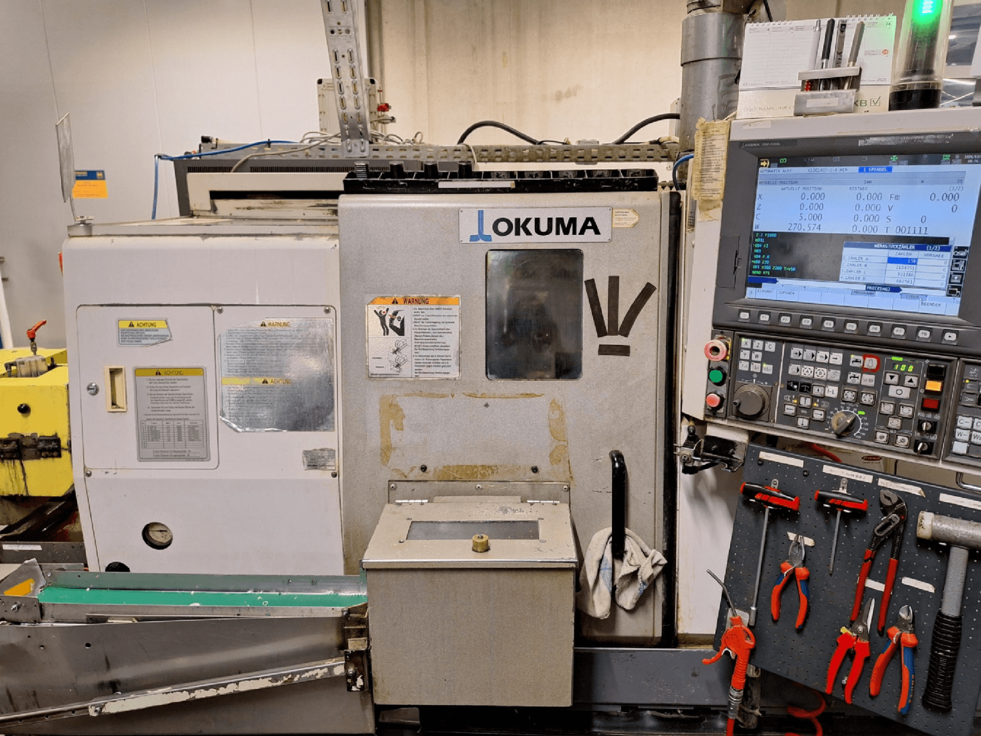 Torno horizontal Okuma LB200-MW, vista frontal, com o painel de controlo e as ferramentas visíveis na lateral.