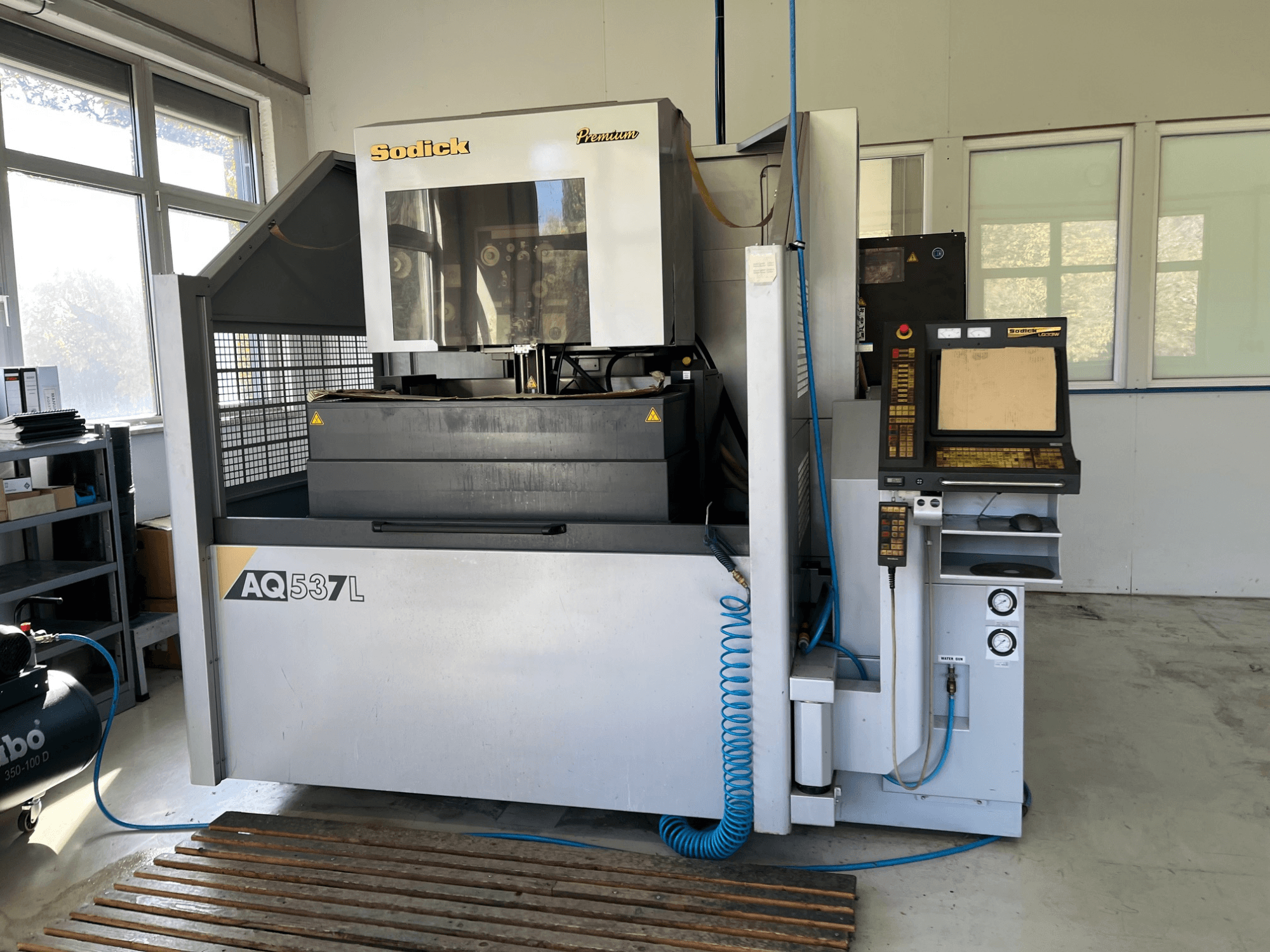 Máquina de descarga eléctrica (EDM) Sodick AQ537L em vista frontal, com painel de controlo, linhas de arrefecimento de água e espaço de trabalho.