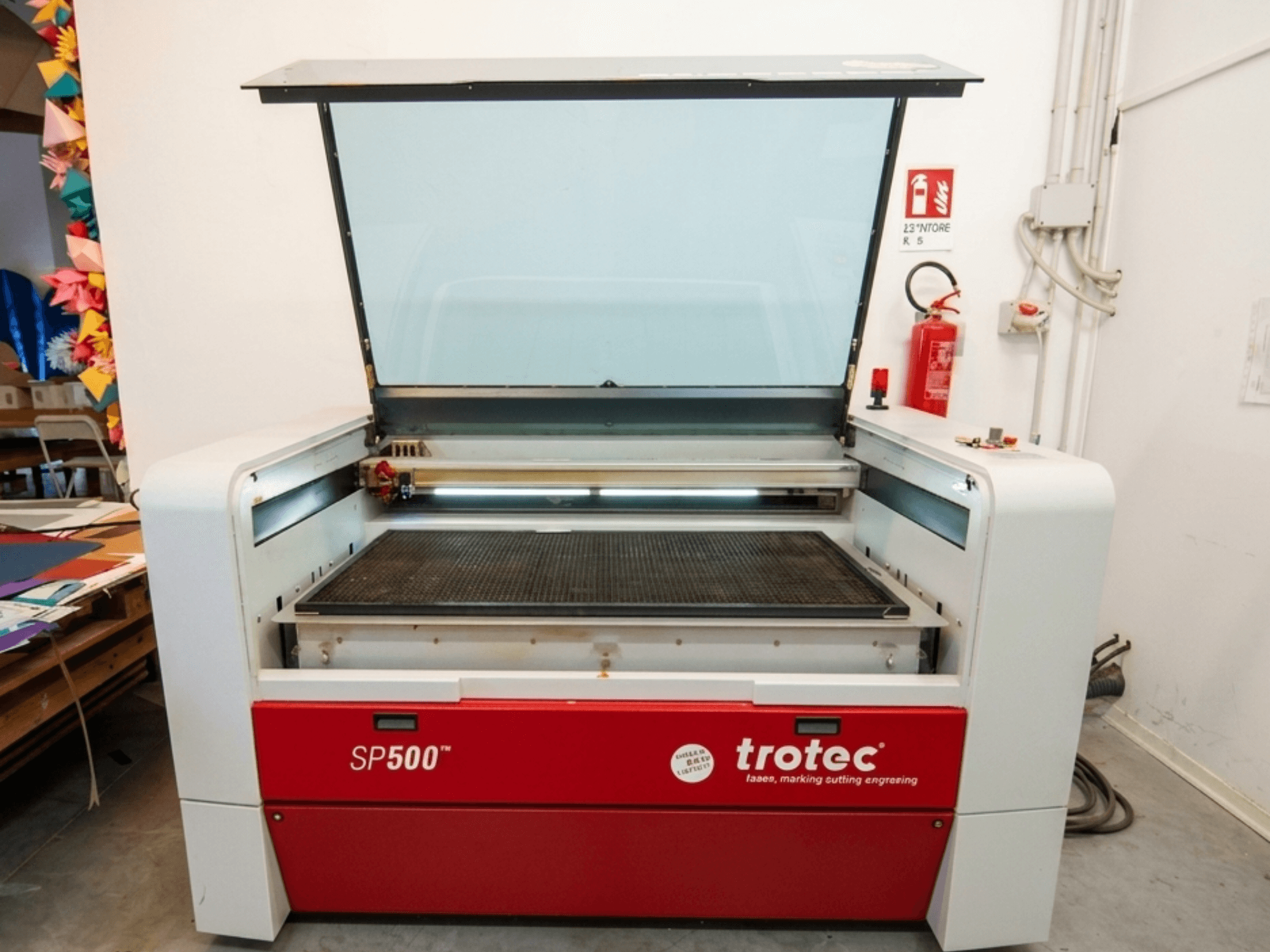 Máquina de gravação a laser Trotec SP500 C200 em vista frontal, com a tampa aberta mostrando a área de trabalho e os controlos.