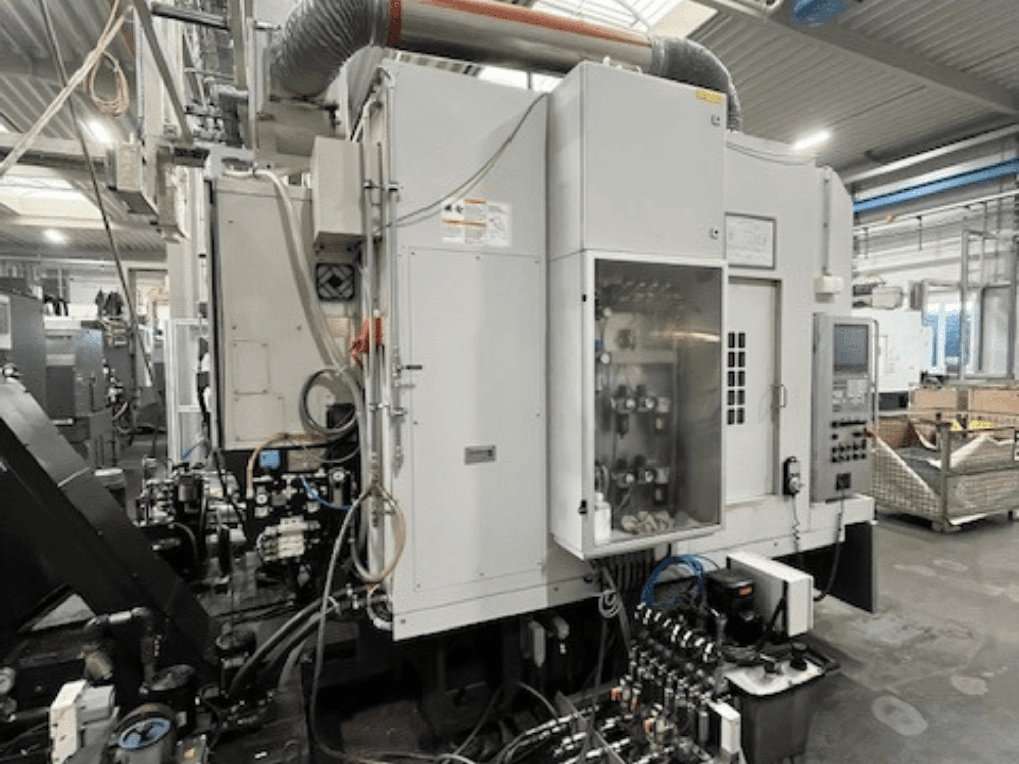 Vista lateral de máquina industrial com painel de controlo e componentes hidráulicos, apresentando detalhes da marca e do modelo.