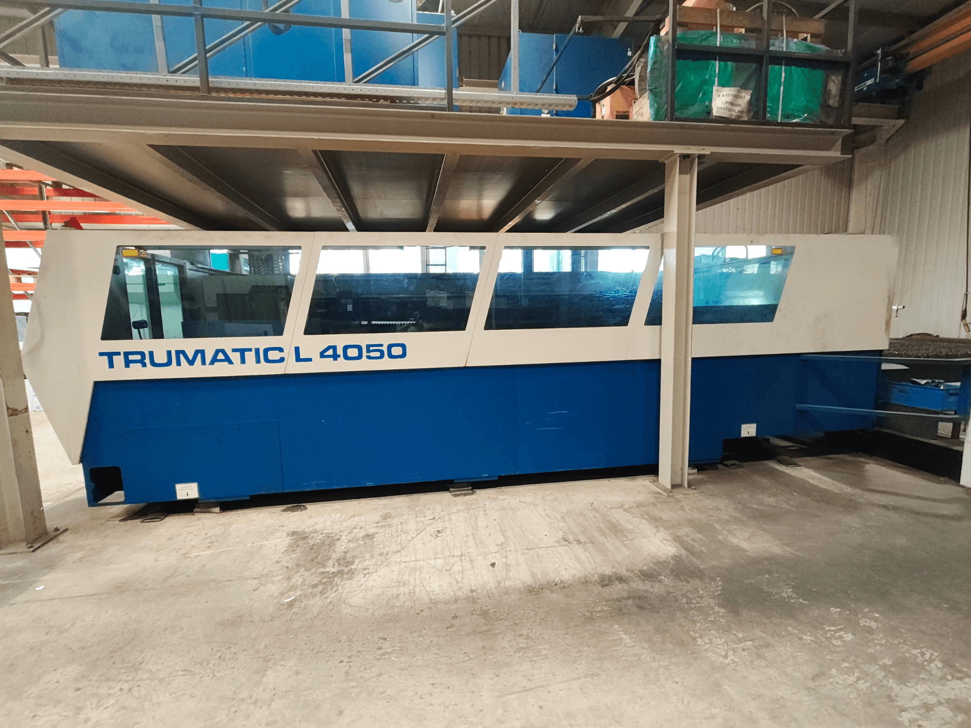 Máquina de corte a laser de CO₂ TRUMPF TruLaser 450 numa vista lateral, com um design azul e branco, com o painel de controlo e a área de trabalho visíveis.