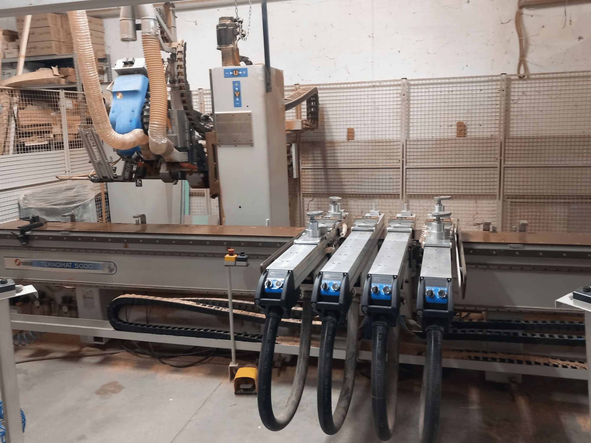 Centro de usinagem de madeira CNC MASTERWOOD TEKNOMAT 5000, vista frontal que mostra o cabeçote de ferramentas e as várias mangueiras de sucção.