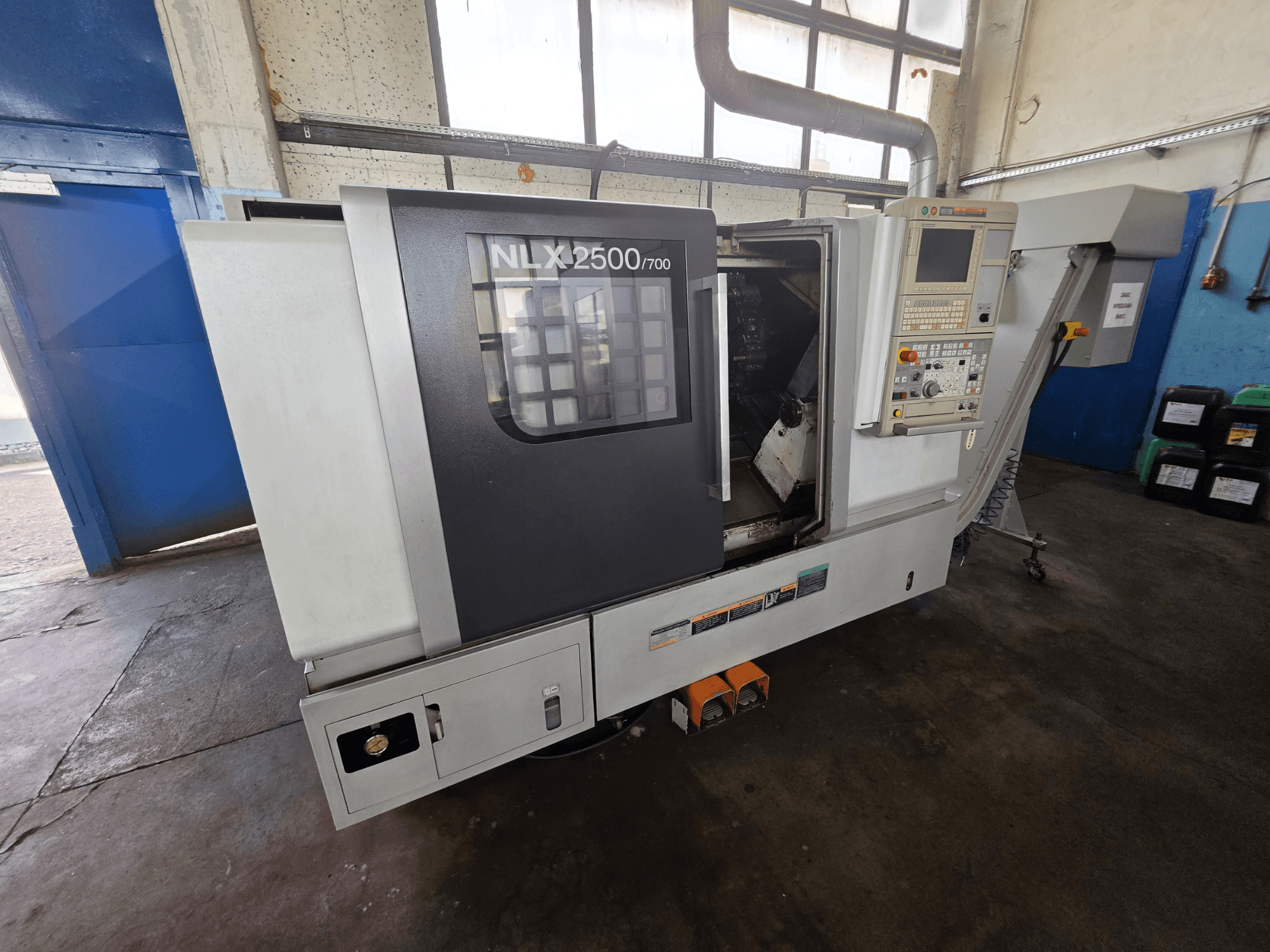 Torno horizontal DMG MORI NLX 2500/700 visto de lado, com o painel de controlo e a área de maquinagem visíveis.