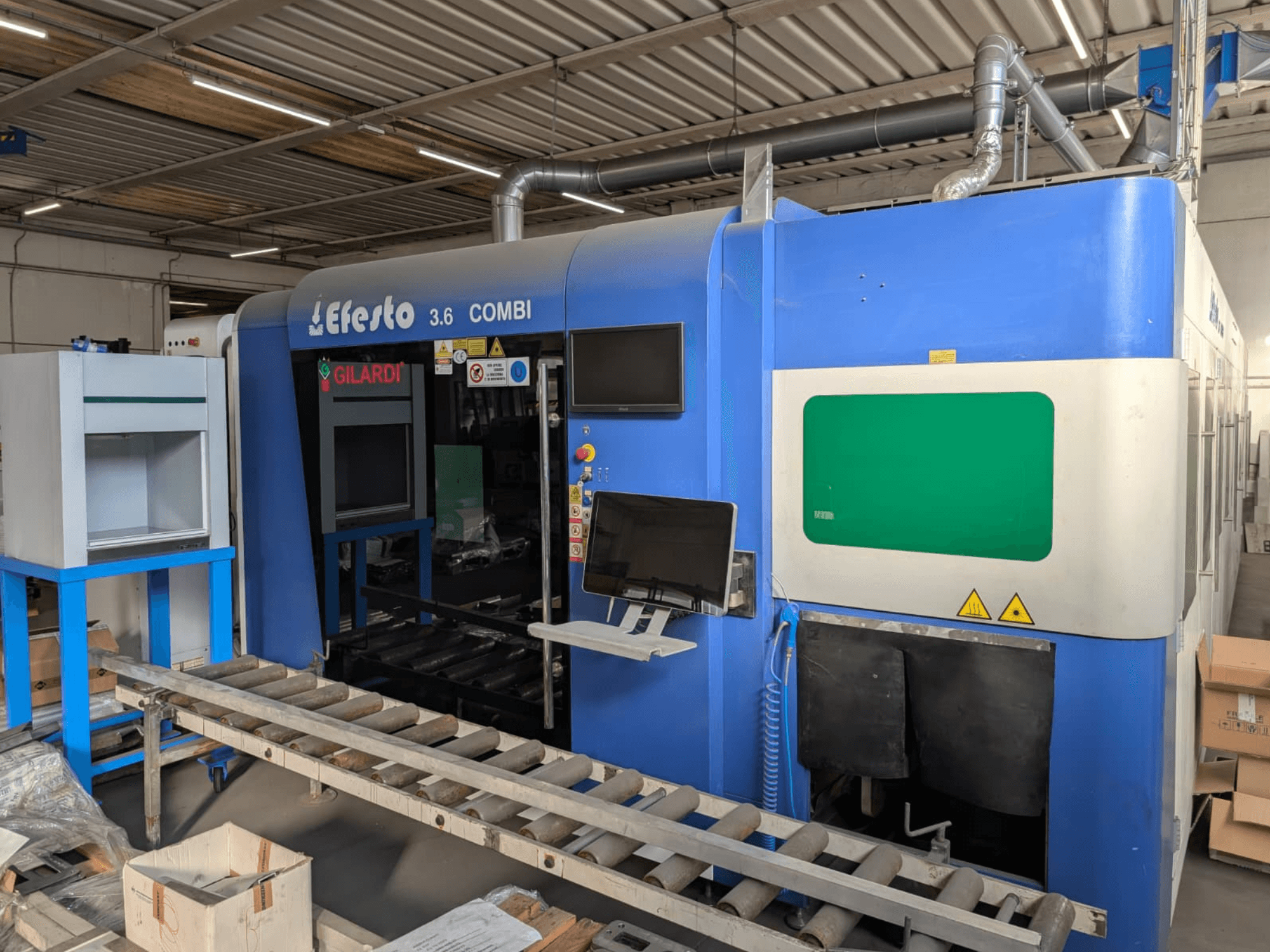 Máquina de corte a laser de fibra EFESTO 3.6 COMBI, vista lateral, com painel de controlo e indicadores de segurança, com exterior azul.