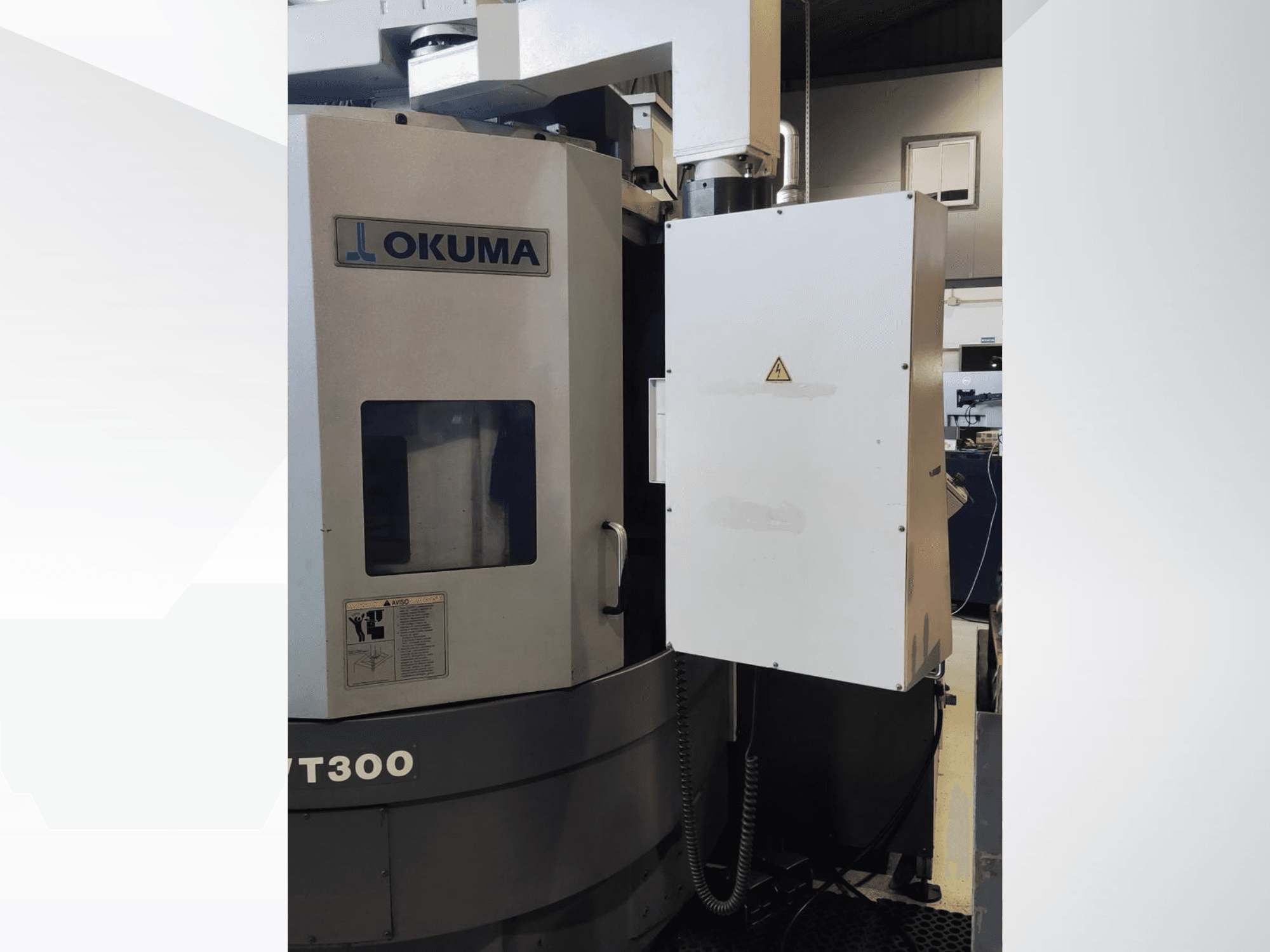 Okuma LVT300 máquina de torneamento vertical, vista frontal, mostrando o painel de controlo e as caraterísticas de segurança rotuladas.
