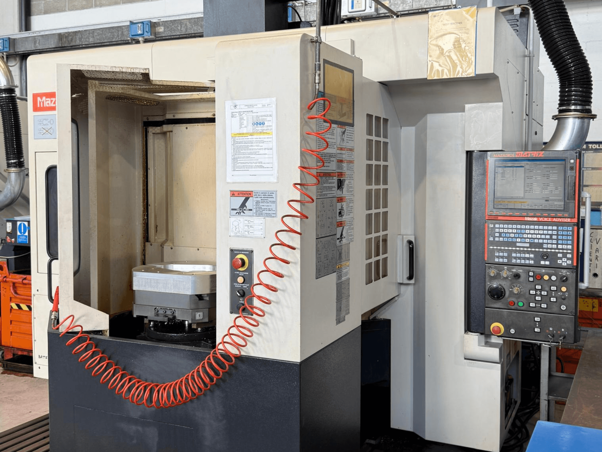 Centro de maquinagem vertical Mazak VARIAXIS I 500, visto de frente, mostrando o painel de controlo, o suporte da peça e a área de armazenamento de ferramentas.
