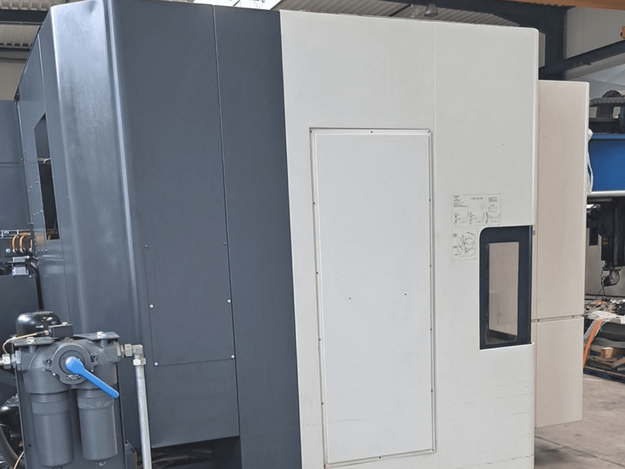 Centro de maquinagem horizontal DMG MORI NHX5000, vista lateral que mostra o painel de controlo e as características mecânicas.
