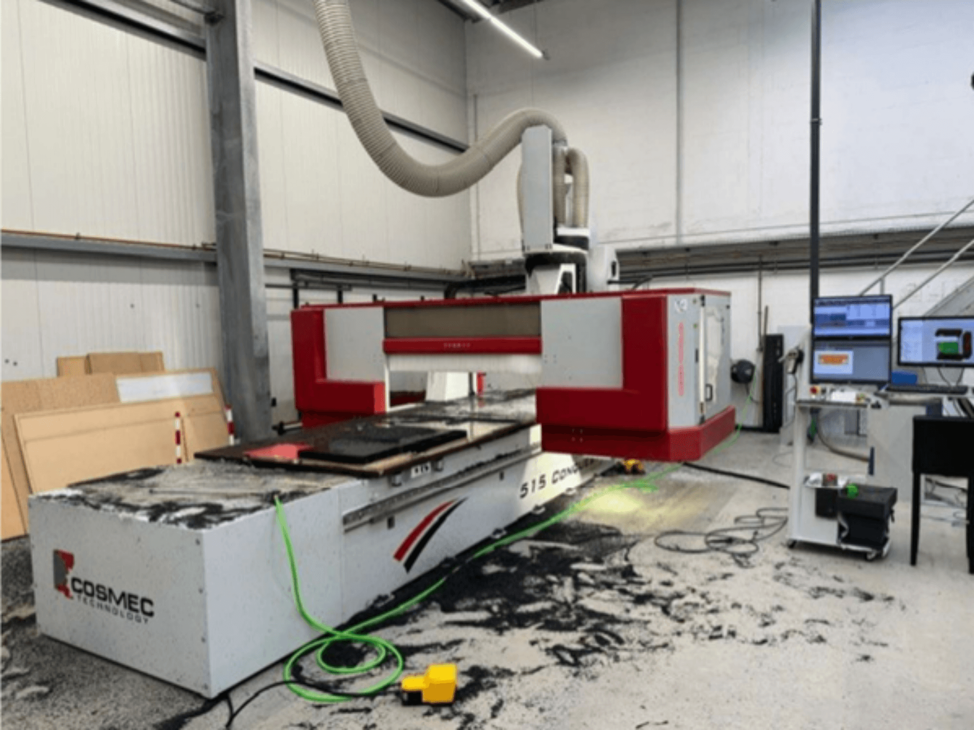 Máquina CNC Cosmec 515 em oficina com um terminal de computador, mostrando uma vista frontal e poeira espalhada na superfície.
